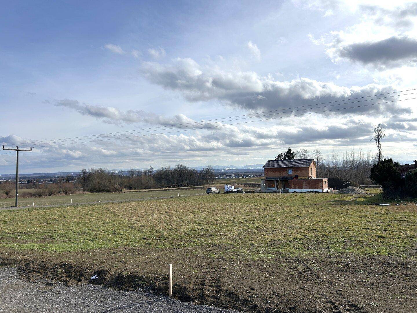 Weitläufiges Grundstück mit Blick auf die Landschaft und ein im Bau befindliches Haus.