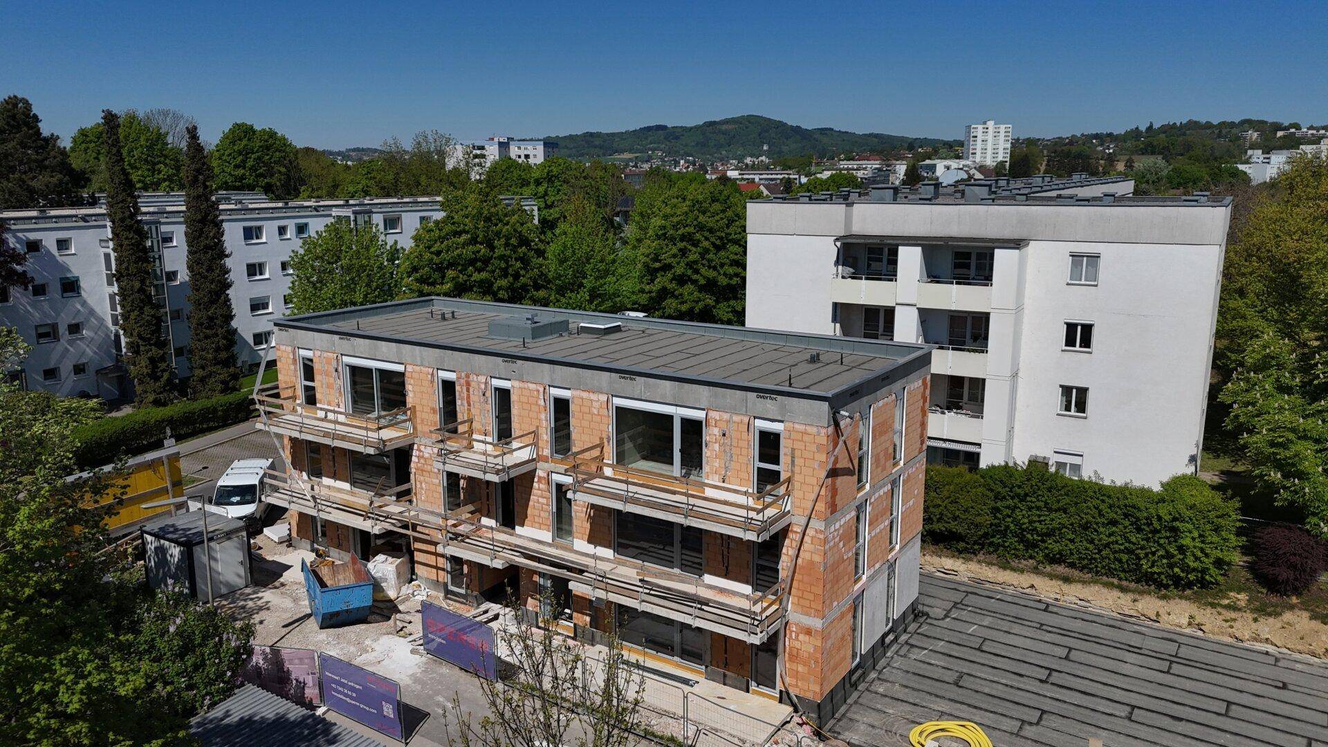 Luftaufnahme des Neubaus in städtischer Umgebung mit weiteren Wohngebäuden.