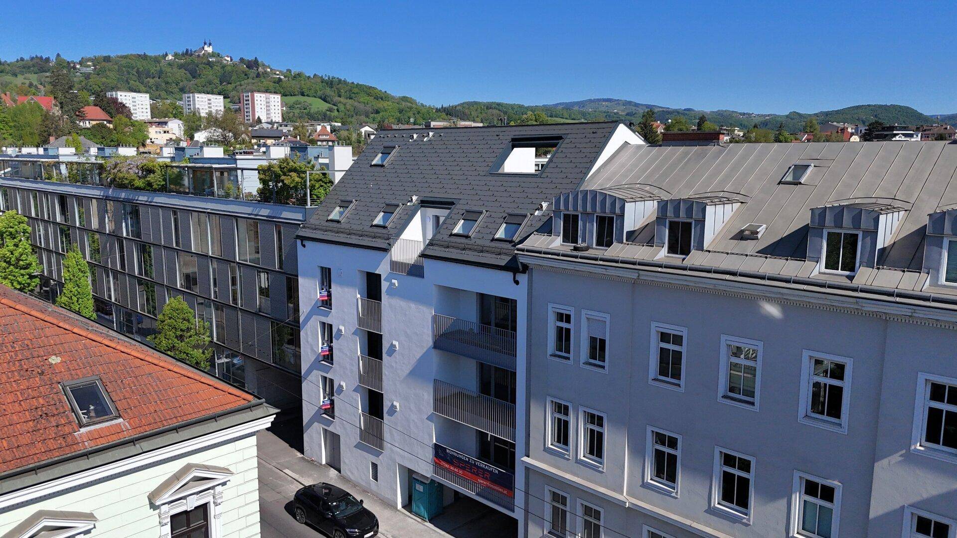 Luftaufnahme des Wohngebäudes mit Satteldach und umliegender Bebauung in grüner Umgebung.
