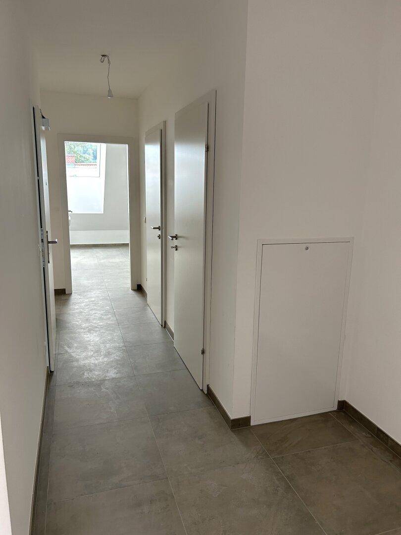 Heller Flur mit Fliesenboden und weißen Türen, der zu weiteren Räumen führt.