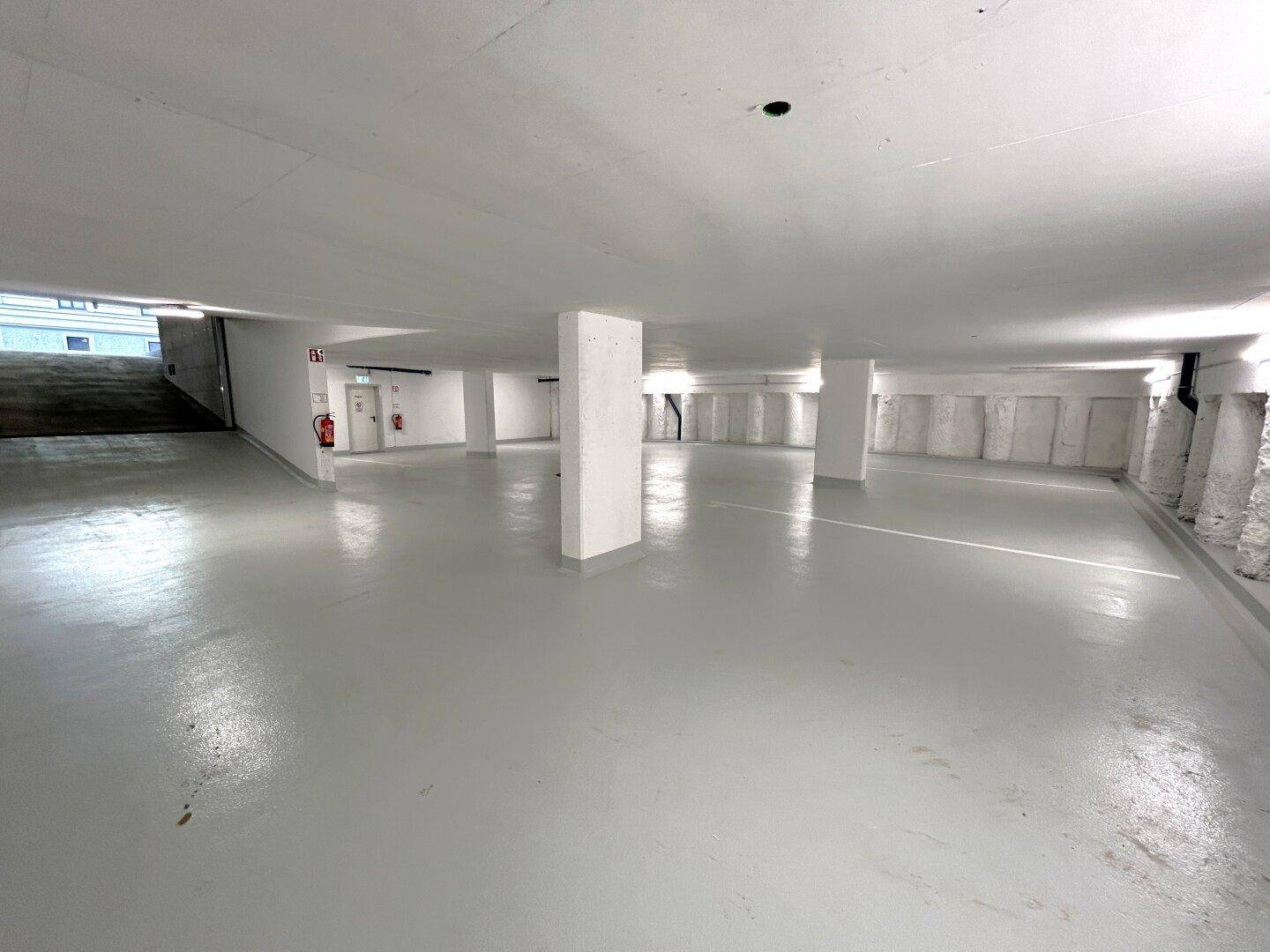 Geräumige Tiefgarage mit hellgrauem Boden und ausreichend Stellplätzen für Fahrzeuge.