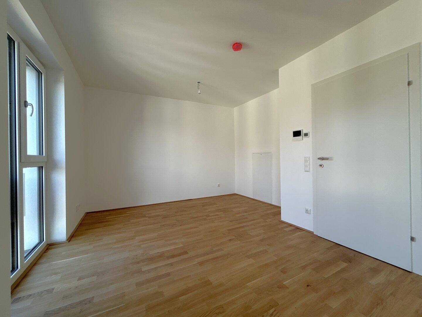 Heller Raum mit Parkettboden und großen Fenstern, ideal als Wohn- oder Schlafzimmer.