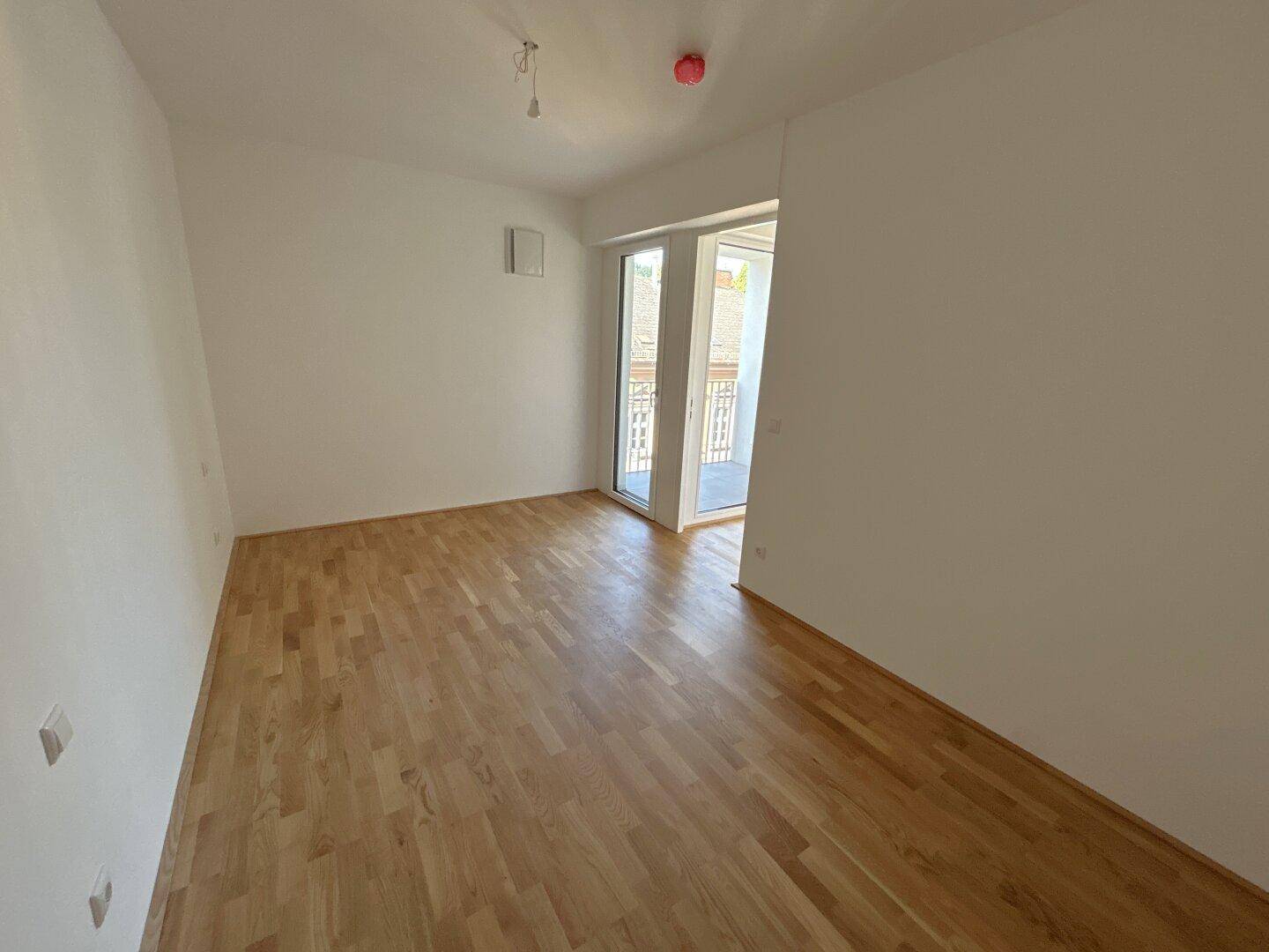 Gemütlicher Raum mit Parkettboden und Zugang zu einem französischen Balkon.