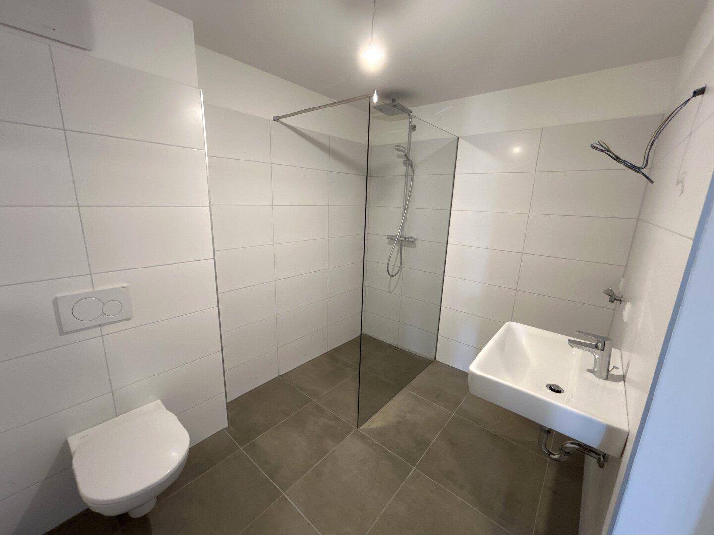 Modernes Badezimmer mit begehbarer Dusche, Wand-WC und stilvollen Fliesen.
