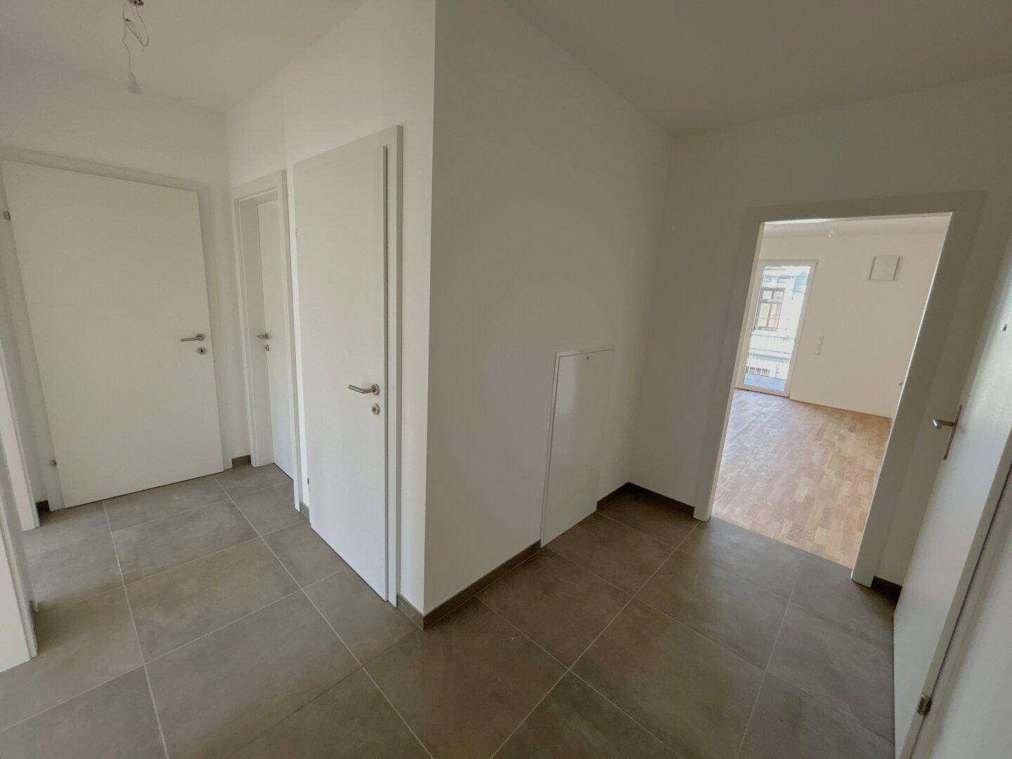 Moderner Flur mit Fliesenboden und mehreren Türen zu den angrenzenden Räumen der Wohnung.