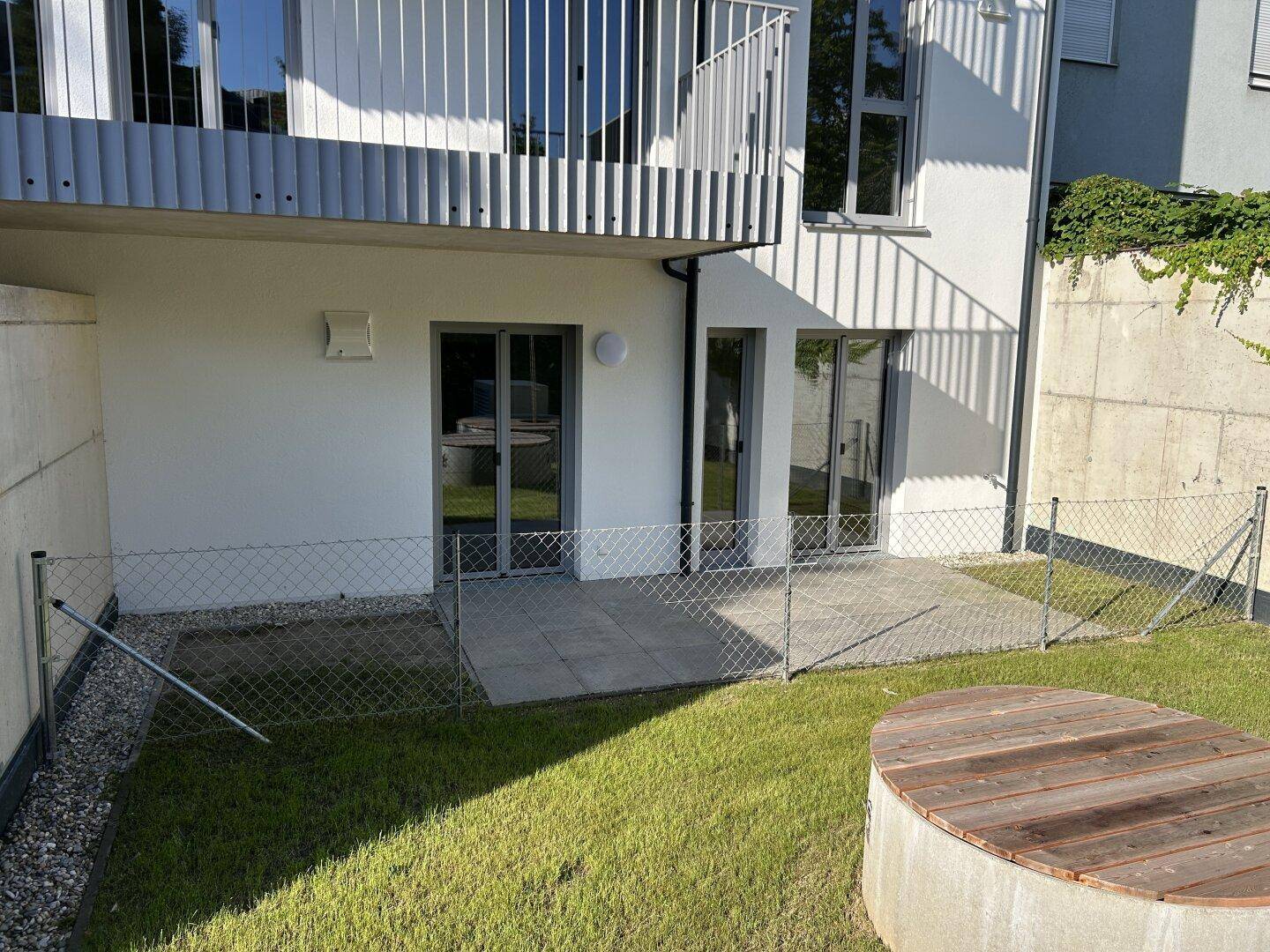Hinterhofgarten mit Rasenfläche, kleiner Terrasse und Zugang zu den Wohnräumen im Erdgeschoss.