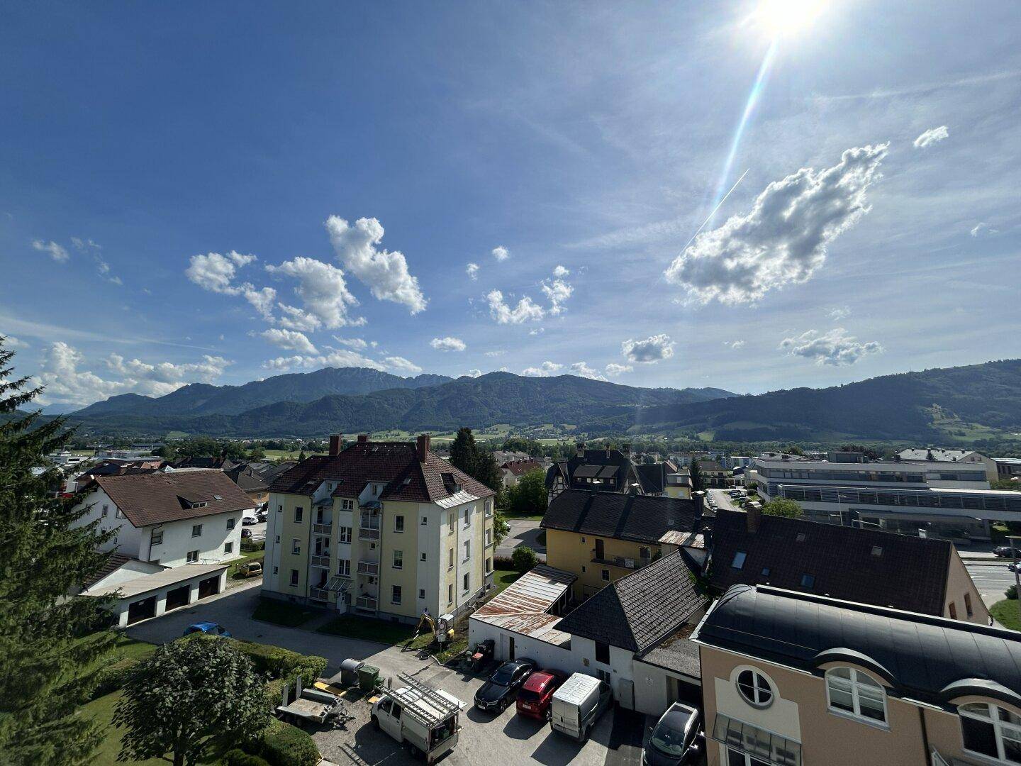 Weitläufiger Blick über die Stadt und die umliegende Berglandschaft an einem sonnigen Tag.