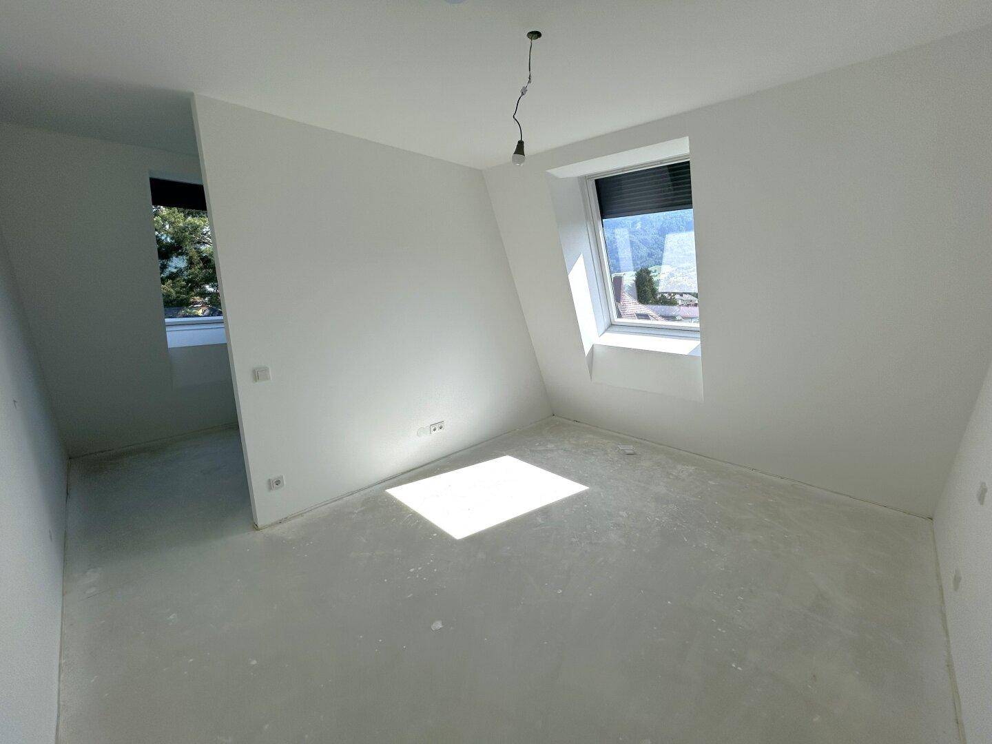 Helles Schlafzimmer im Dachgeschoss mit schrägen Wänden und einem Dachfenster.