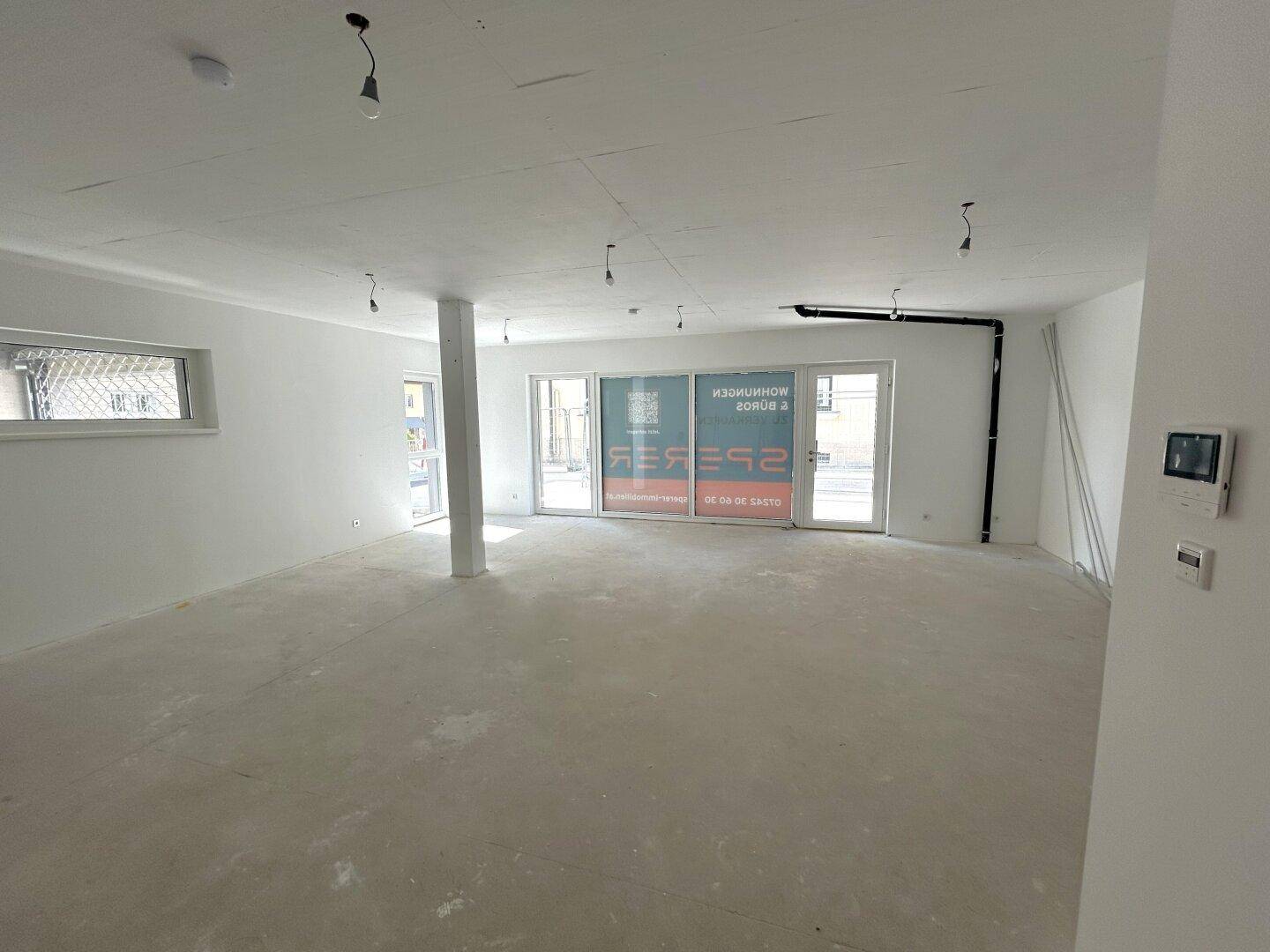 Heller, leerer Gewerberaum im Rohbau mit großen Fenstern und viel Tageslicht, bereit für den Ausbau.