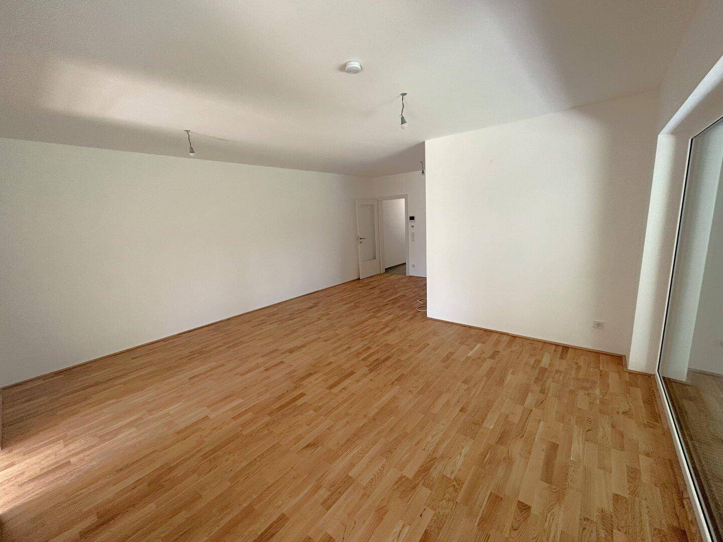 Geräumiger, heller Raum mit Holzboden und weißen Wänden, bereit zur individuellen Gestaltung.