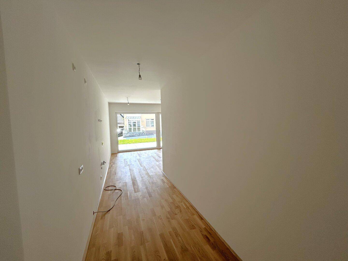 Langer, heller Flur mit Holzboden, der zu weiteren Räumen führt.