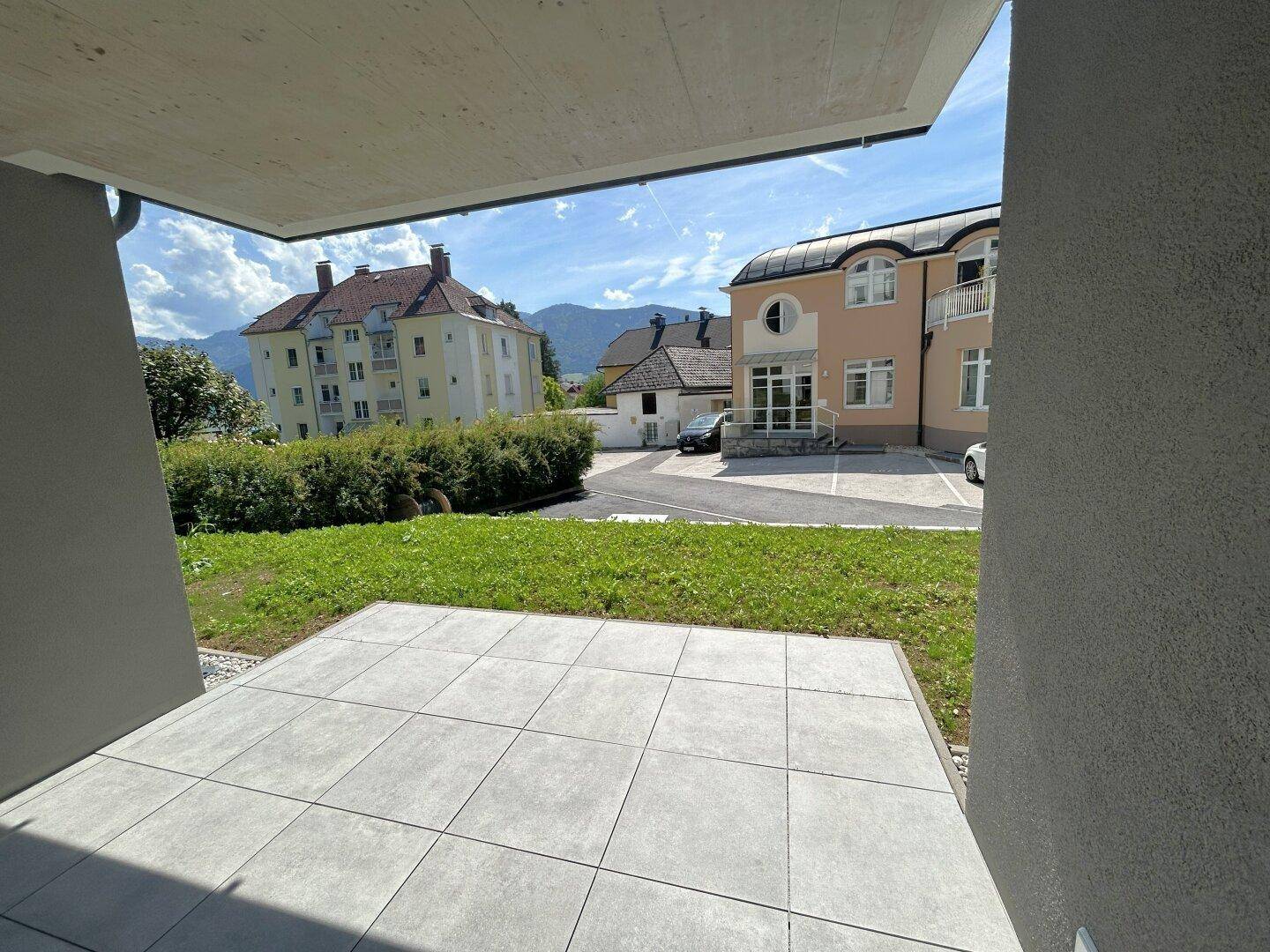 Blick von der Terrasse auf die grüne Umgebung und die umliegenden Gebäude.