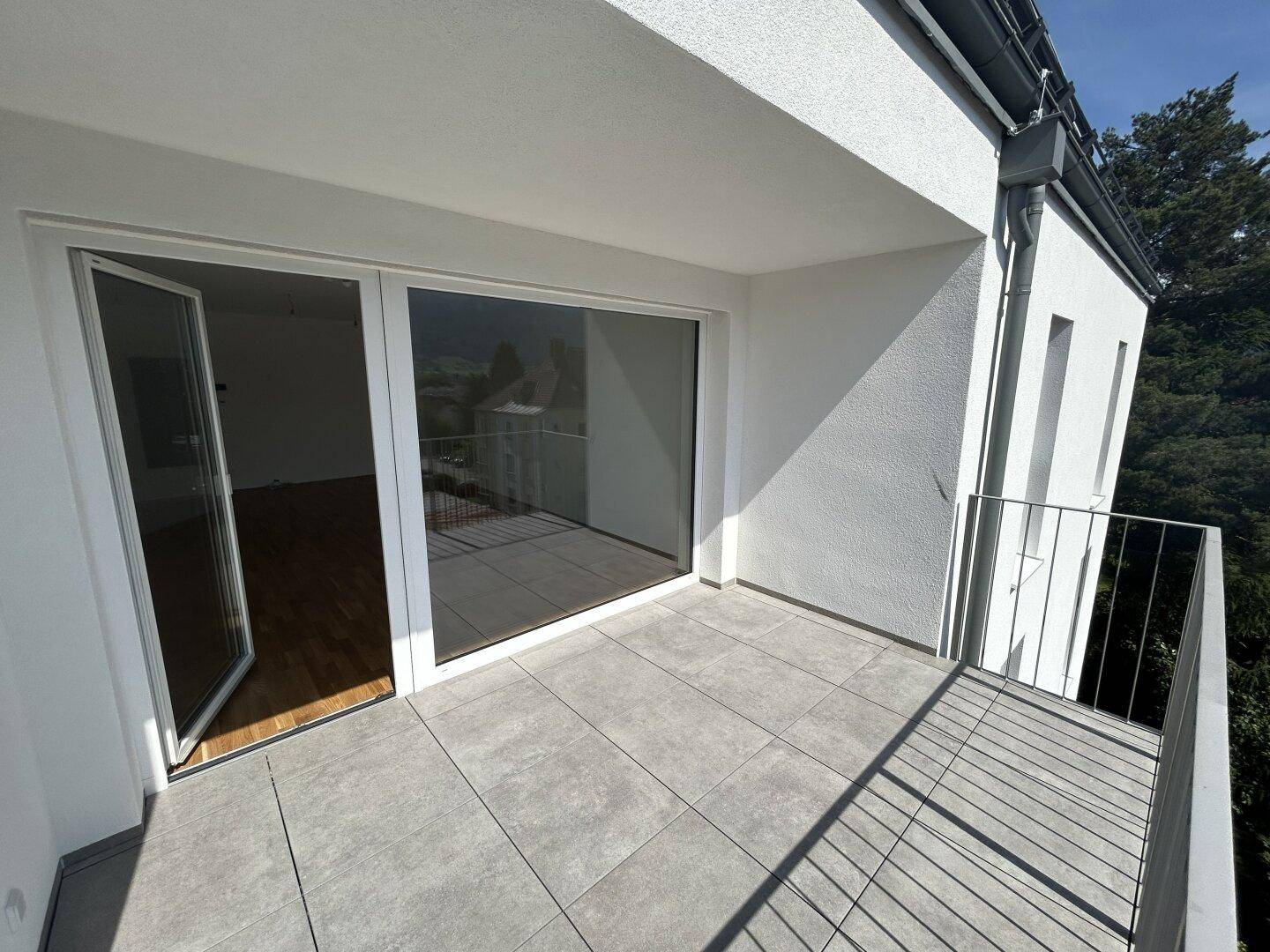 Geräumiger Balkon mit modernen Fliesen und Metallgeländer, ideal für entspannte Stunden im Freien.