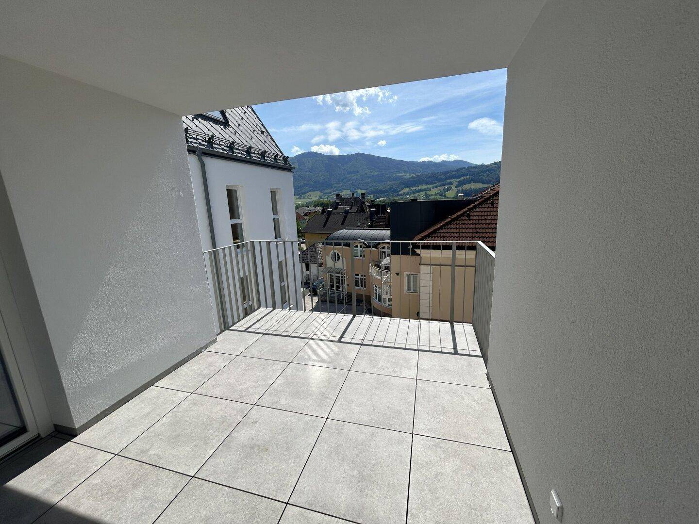 Heller Balkon mit Fliesenboden und weitem Blick auf die umliegende Berglandschaft.