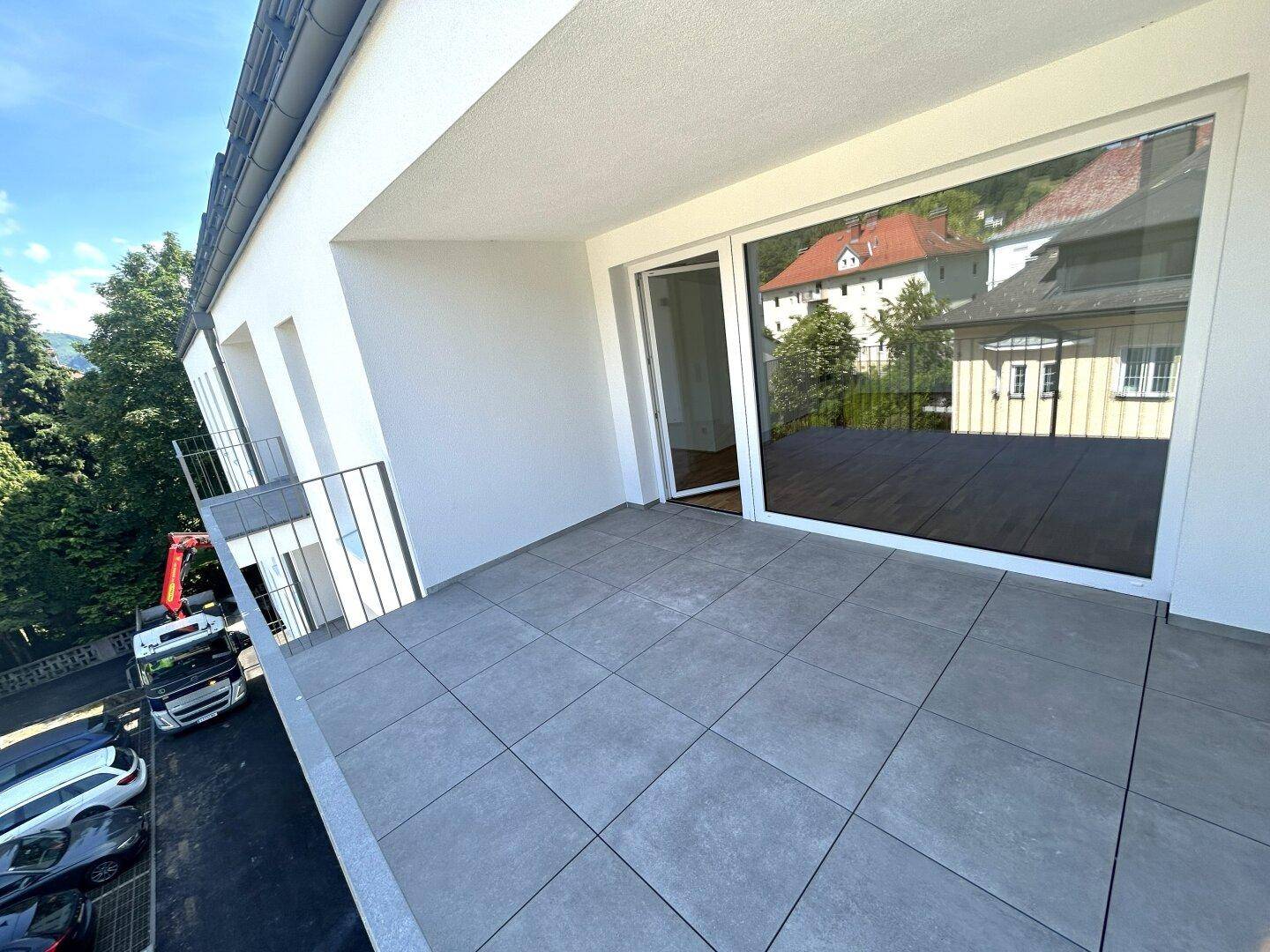 Heller Balkon mit großen Schiebetüren zum Innenbereich und Blick auf die Umgebung.