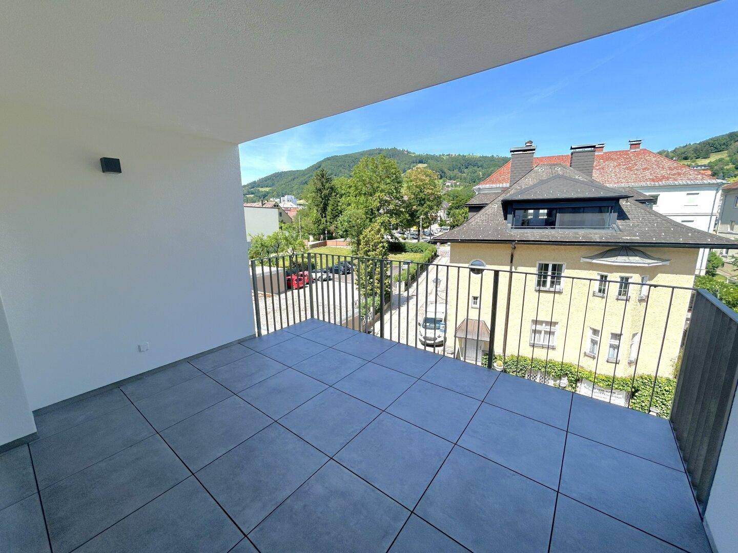 Geräumiger Balkon mit Fliesenboden und modernem Metallgeländer, bietet einen weiten Ausblick.
