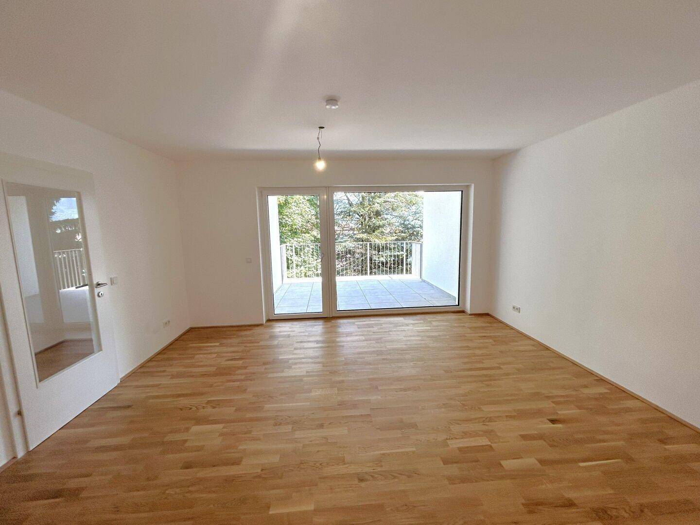Lichtdurchflutetes Wohnzimmer mit Holzboden und direktem Zugang zum Außenbereich.