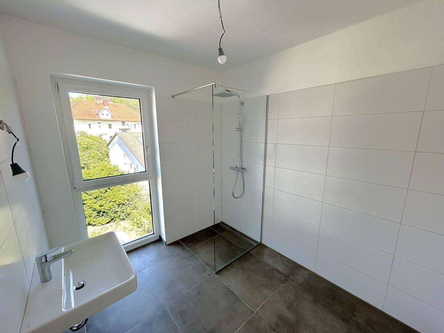 Modernes Badezimmer mit begehbarer Dusche, Wandwaschbecken und Fenster für Tageslicht.