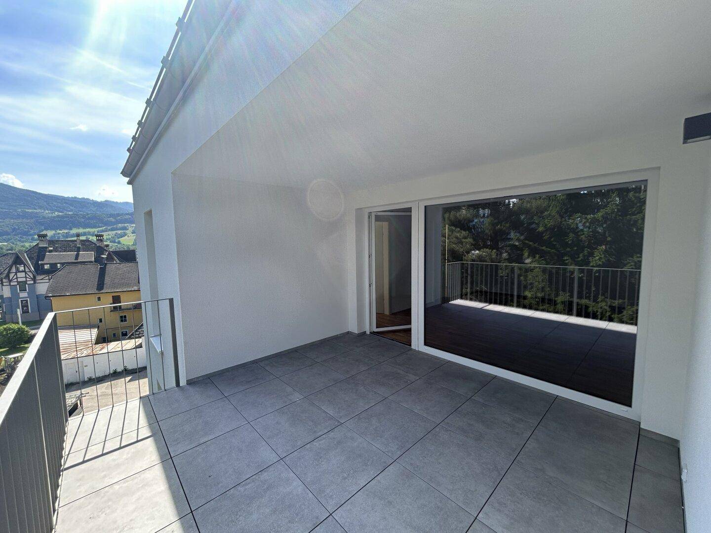 Großer Balkon mit Fliesenboden, Metallgeländer und weitem Blick auf die umliegende Berglandschaft.