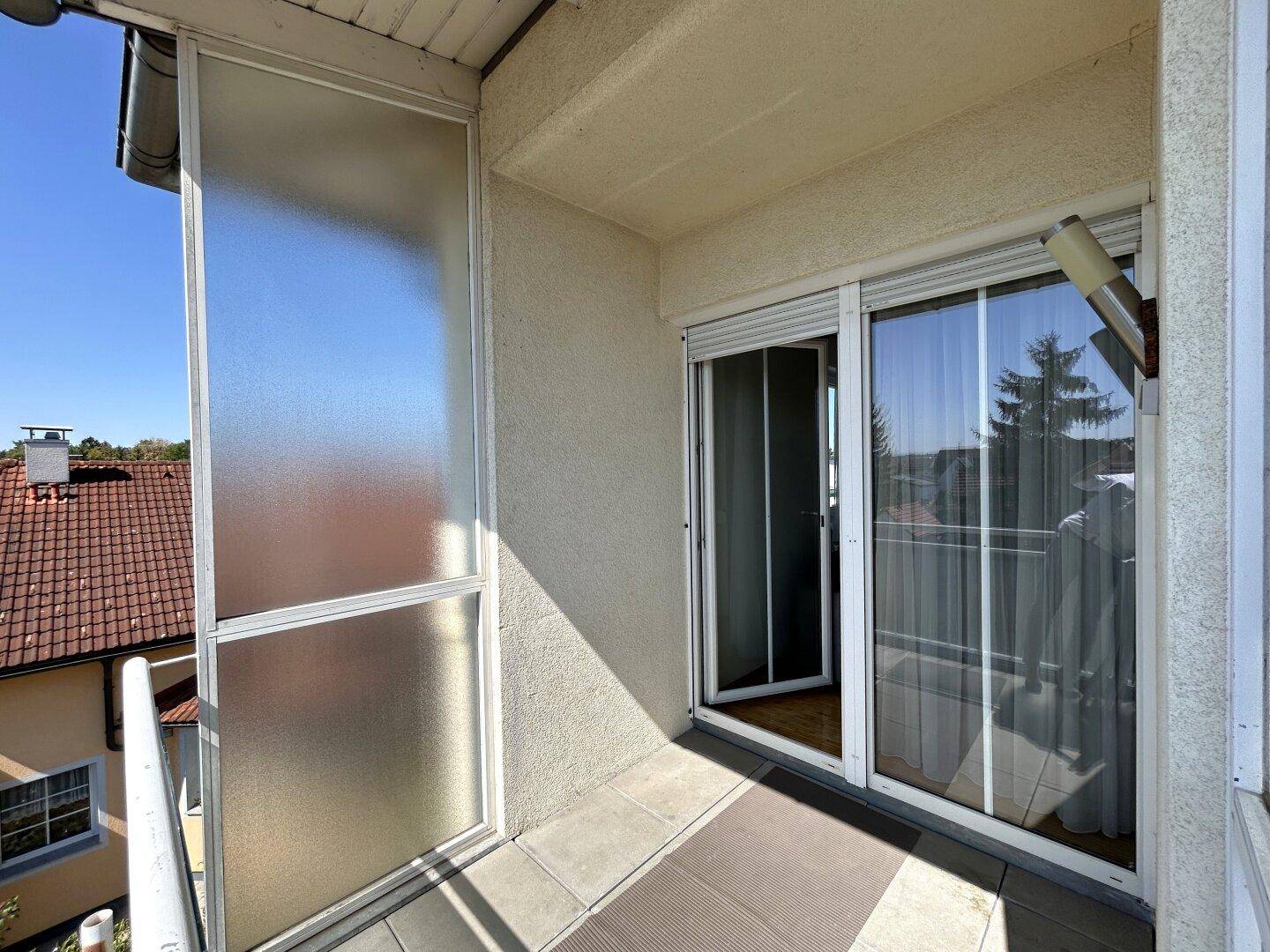 Balkon mit Milchglas-Seitenwänden und Zugang zum Innenbereich der Wohnung, bietet Privatsphäre.