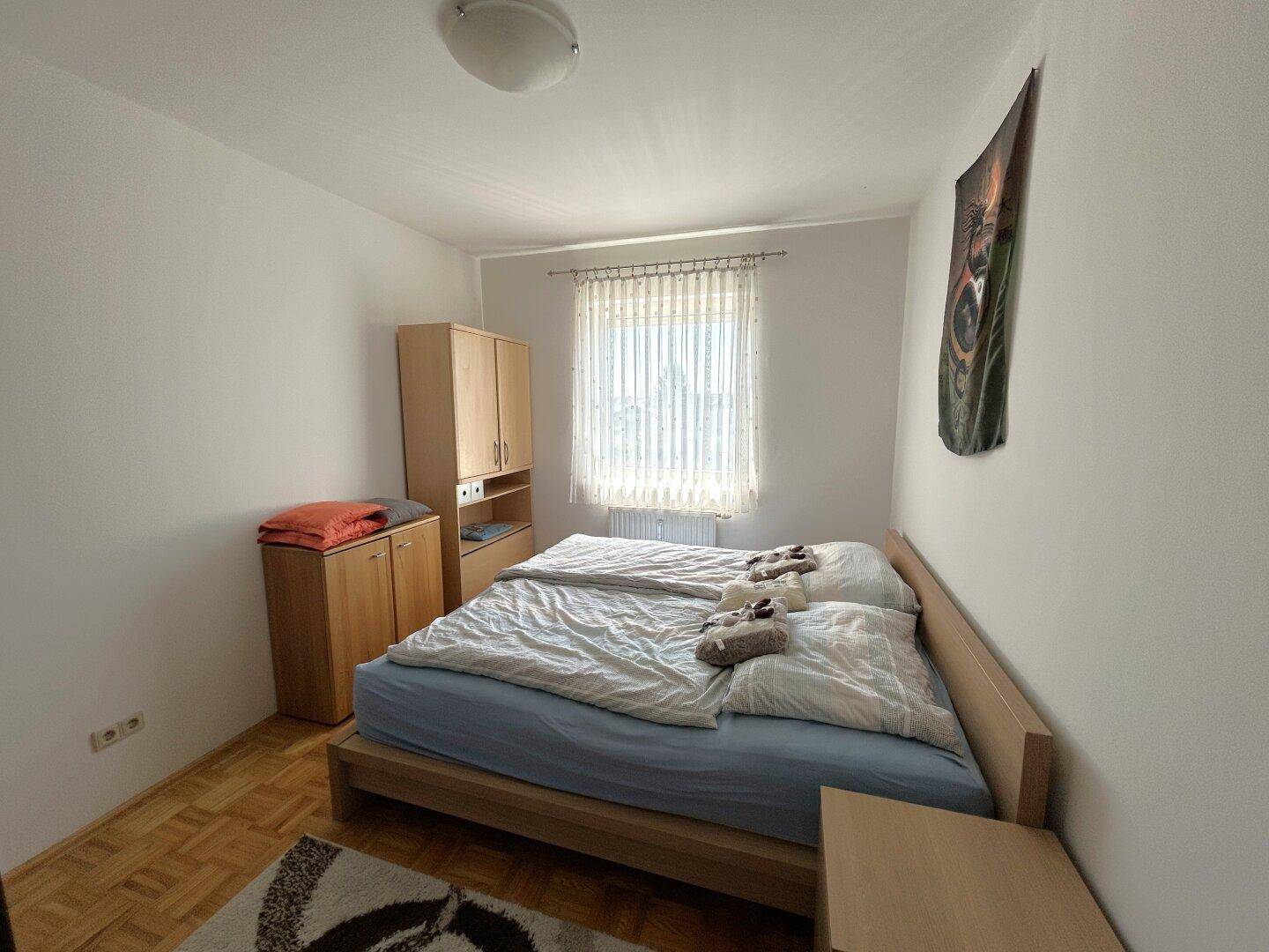 Schlafzimmer mit Doppelbett, hellen Holzmöbeln und Laminatboden, bietet eine gemütliche Atmosphäre.