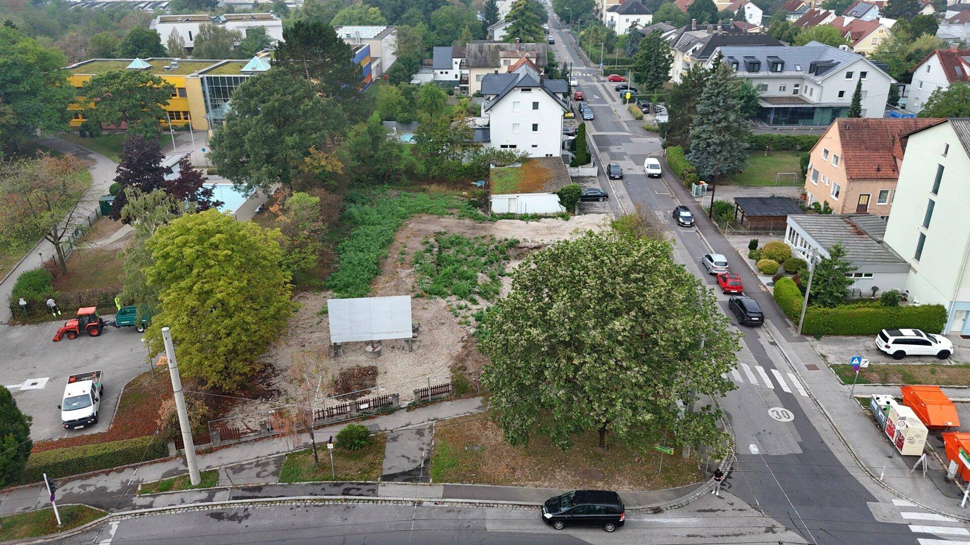 Luftaufnahme eines unbebauten Grundstücks in einer Wohngegend mit angrenzenden Straßen und Grünflächen.