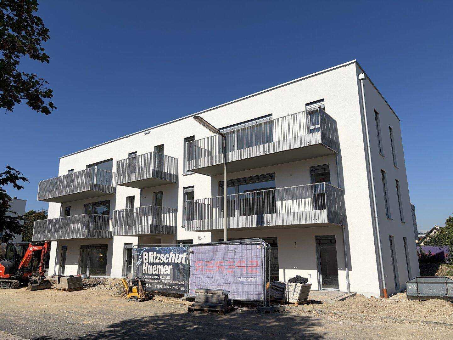 Fertigstellung eines modernen Wohnkomplexes mit hellen Fassaden und zahlreichen Balkonen unter blauem Himmel.