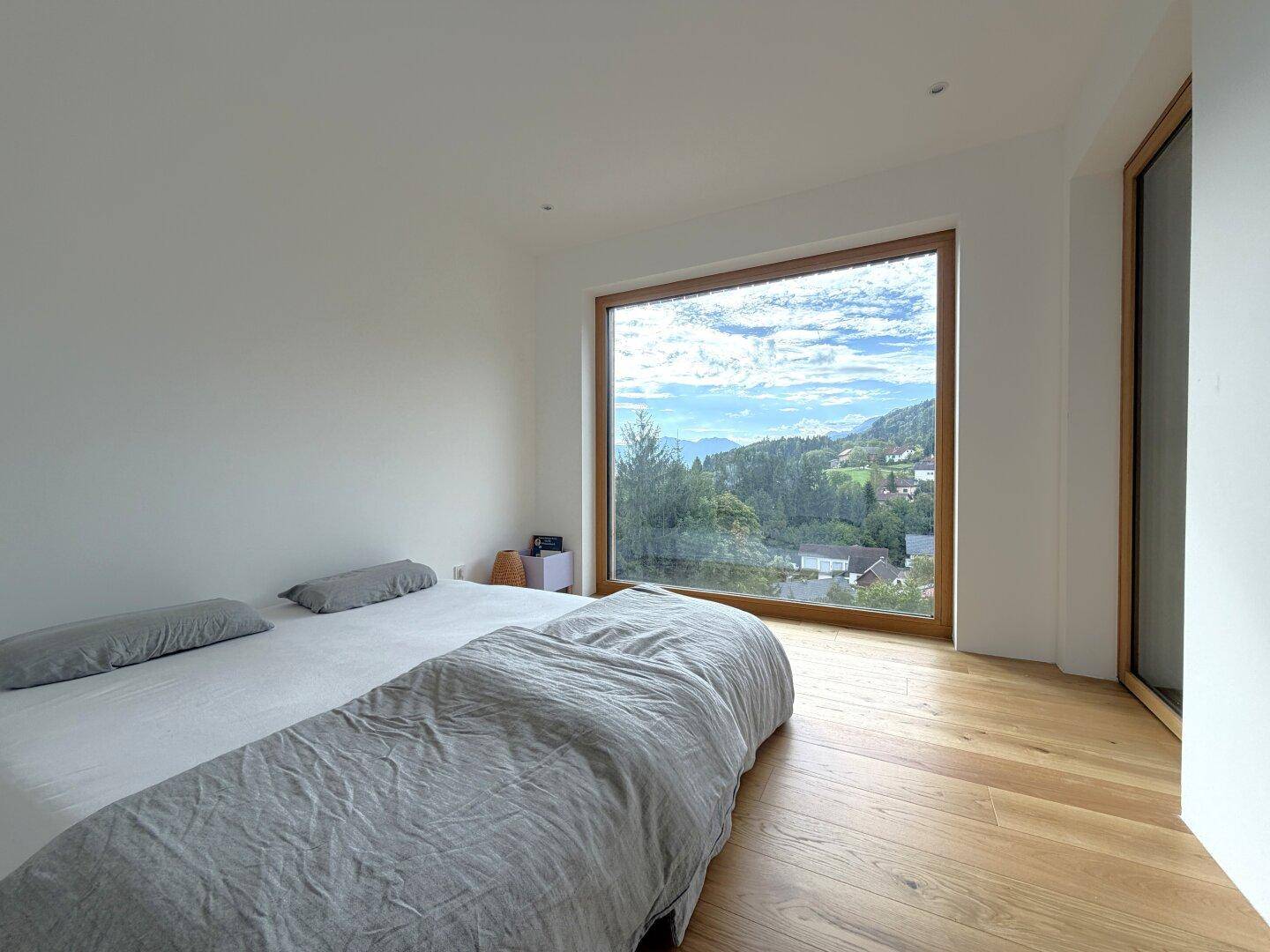 Schlafzimmer mit großem Fenster, das einen weiten Blick auf die umliegende Landschaft bietet.