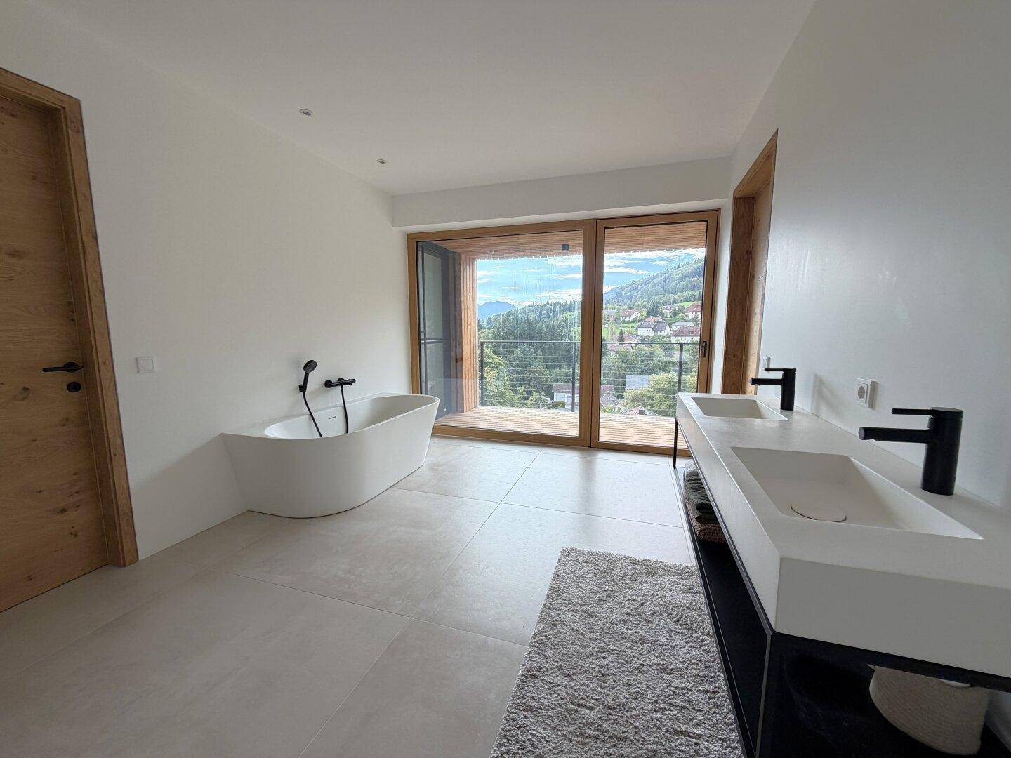 Modernes Badezimmer mit freistehender Badewanne, Doppelwaschbecken und Zugang zur Terrasse.
