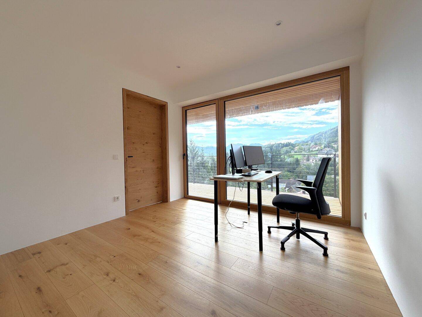 Arbeitszimmer mit Holzboden, großem Fenster und weitem Blick auf die Landschaft.