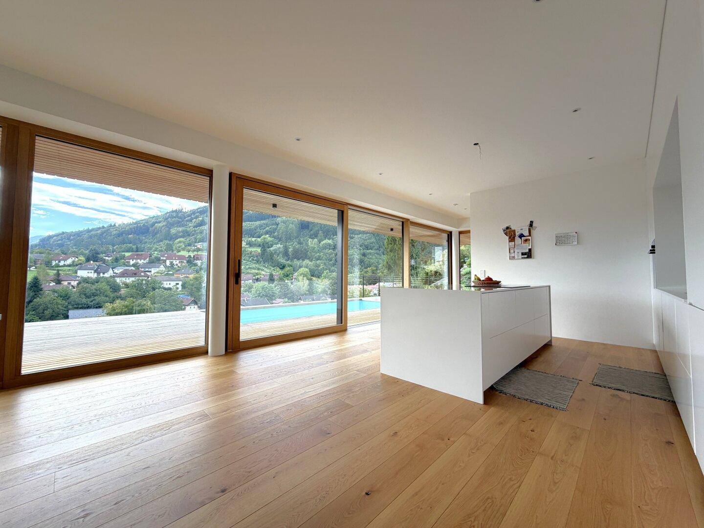 Moderne Küche mit Kochinsel und großen Schiebetüren, die den Blick auf den Pool und die Landschaft freigeben.