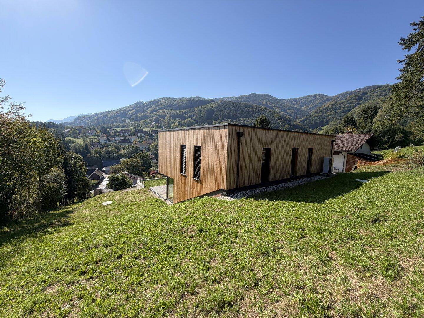 Modernes Holzhaus in idyllischer Hanglage mit weitem Blick über die umliegende Landschaft.