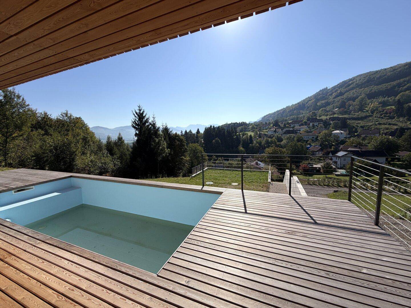 Holzterrasse mit integriertem Pool und atemberaubendem Panoramablick auf die Berge und das Tal.