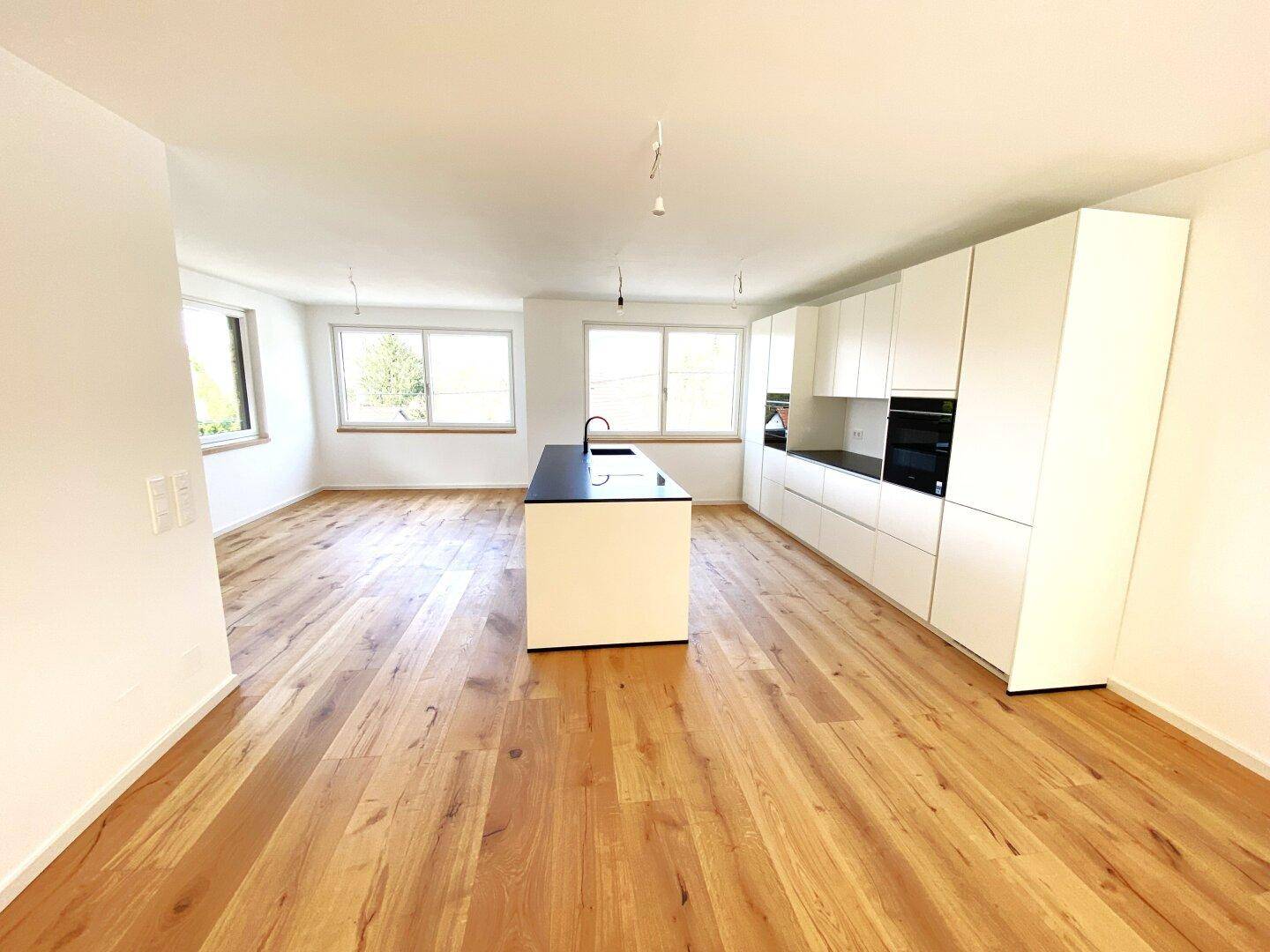 Geräumige, offene Küche mit minimalistischem Design, weißer Schrankfronten und Eichenparkett.
