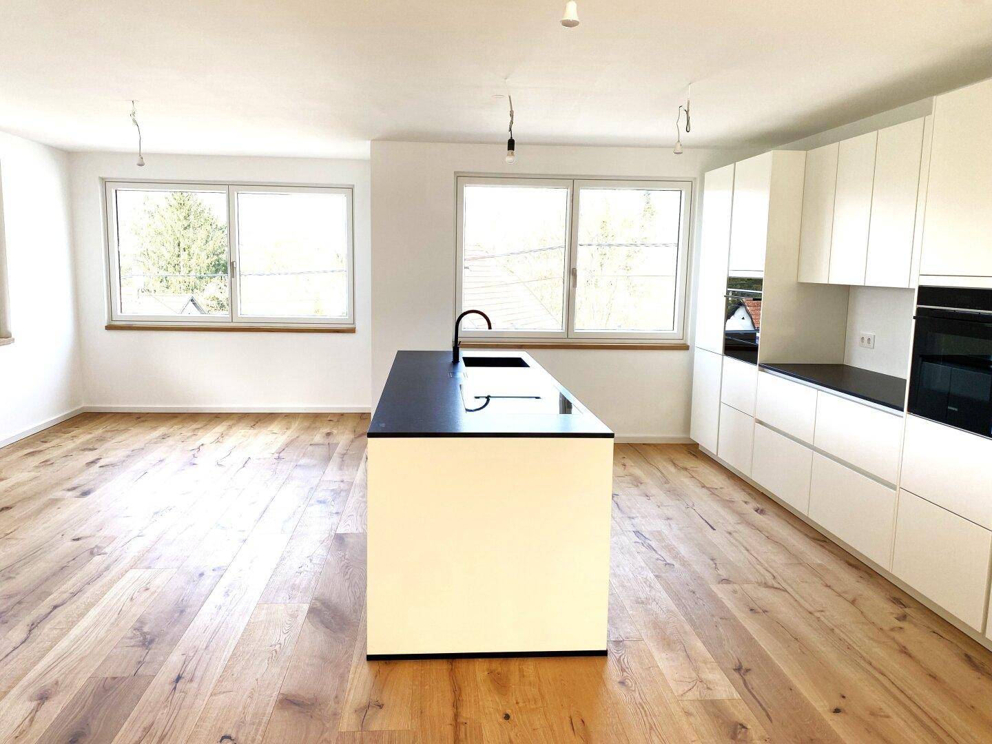 Helle, moderne Küche mit weißer Einbauküche, Kochinsel und hochwertigem Holzparkettboden.