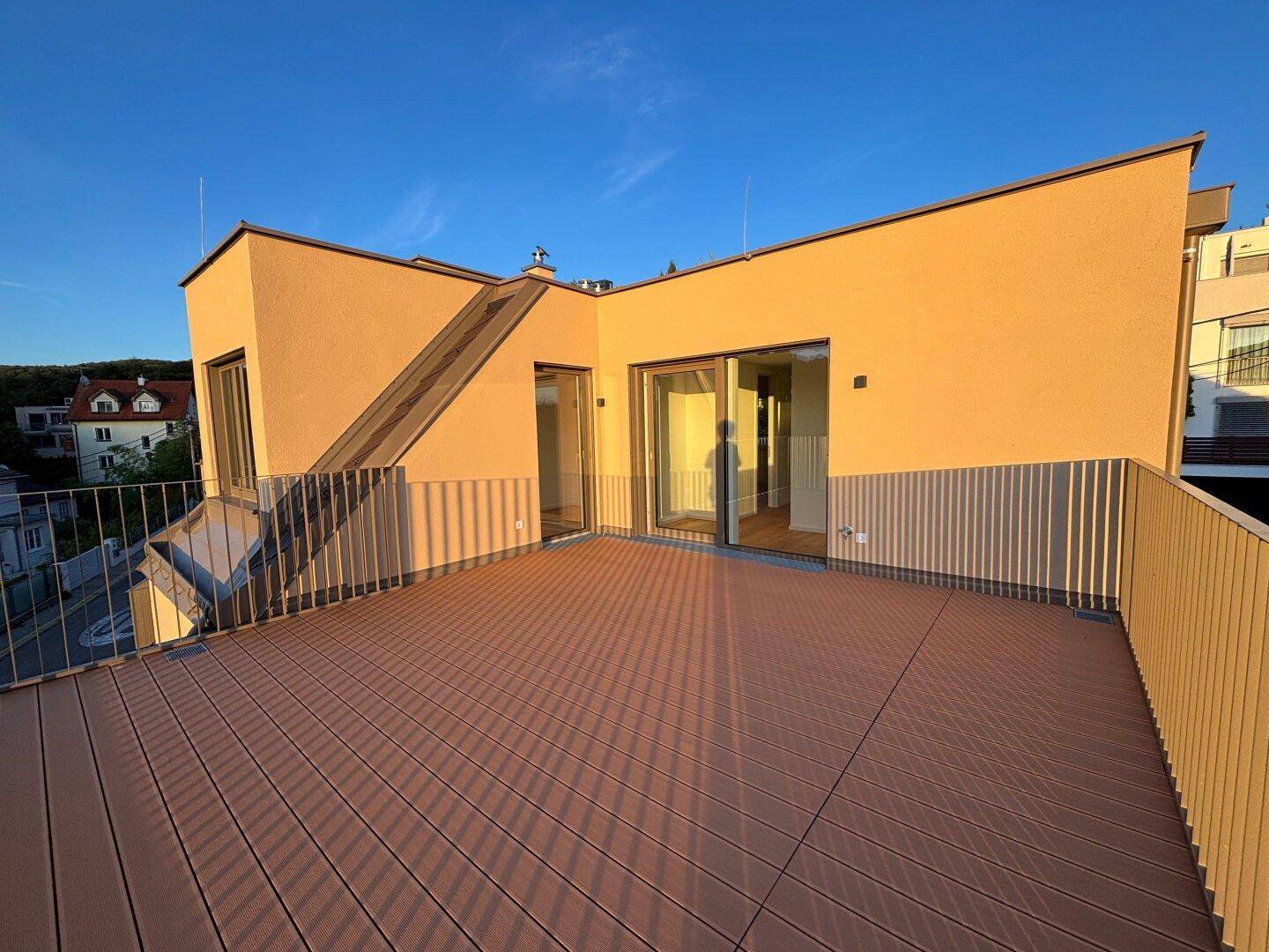 Geräumige Dachterrasse mit Holzboden und Zugang zu den Innenräumen, ideal für Entspannung.