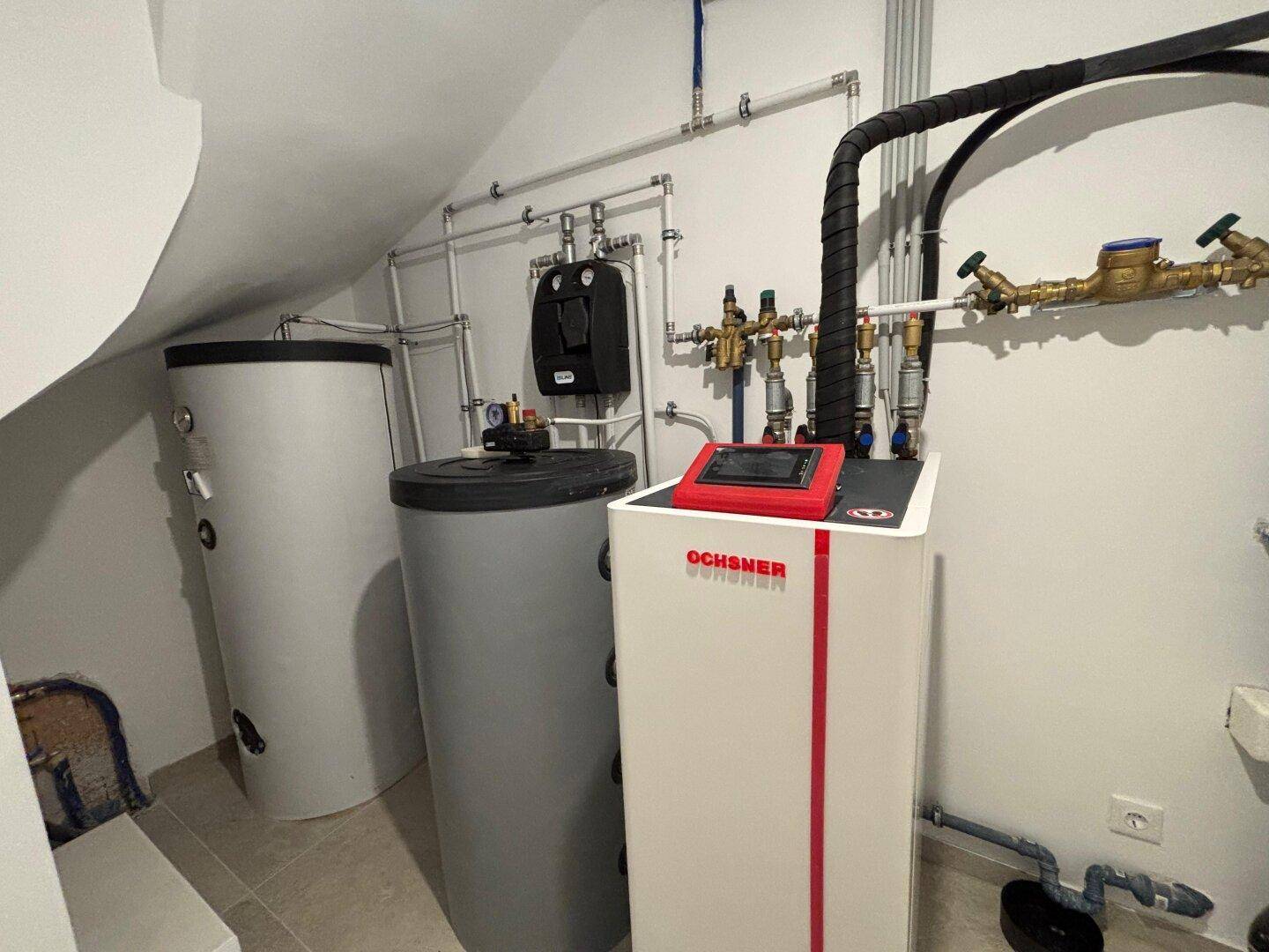 Detailansicht der Ochsner Wärmepumpe und der Warmwasserspeicher im Technikraum.