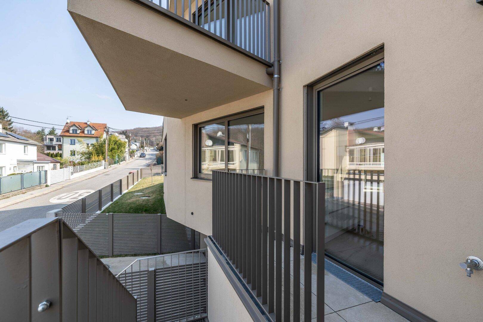 Blick von einem Balkon auf die Straße und die umliegenden Häuser in einer ruhigen Wohngegend.