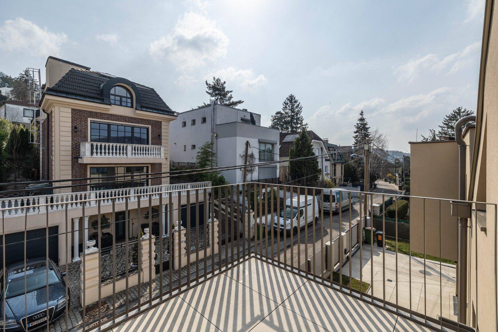 Balkon mit Blick auf die Straße und die benachbarten Häuser mit klassischer und moderner Architektur.