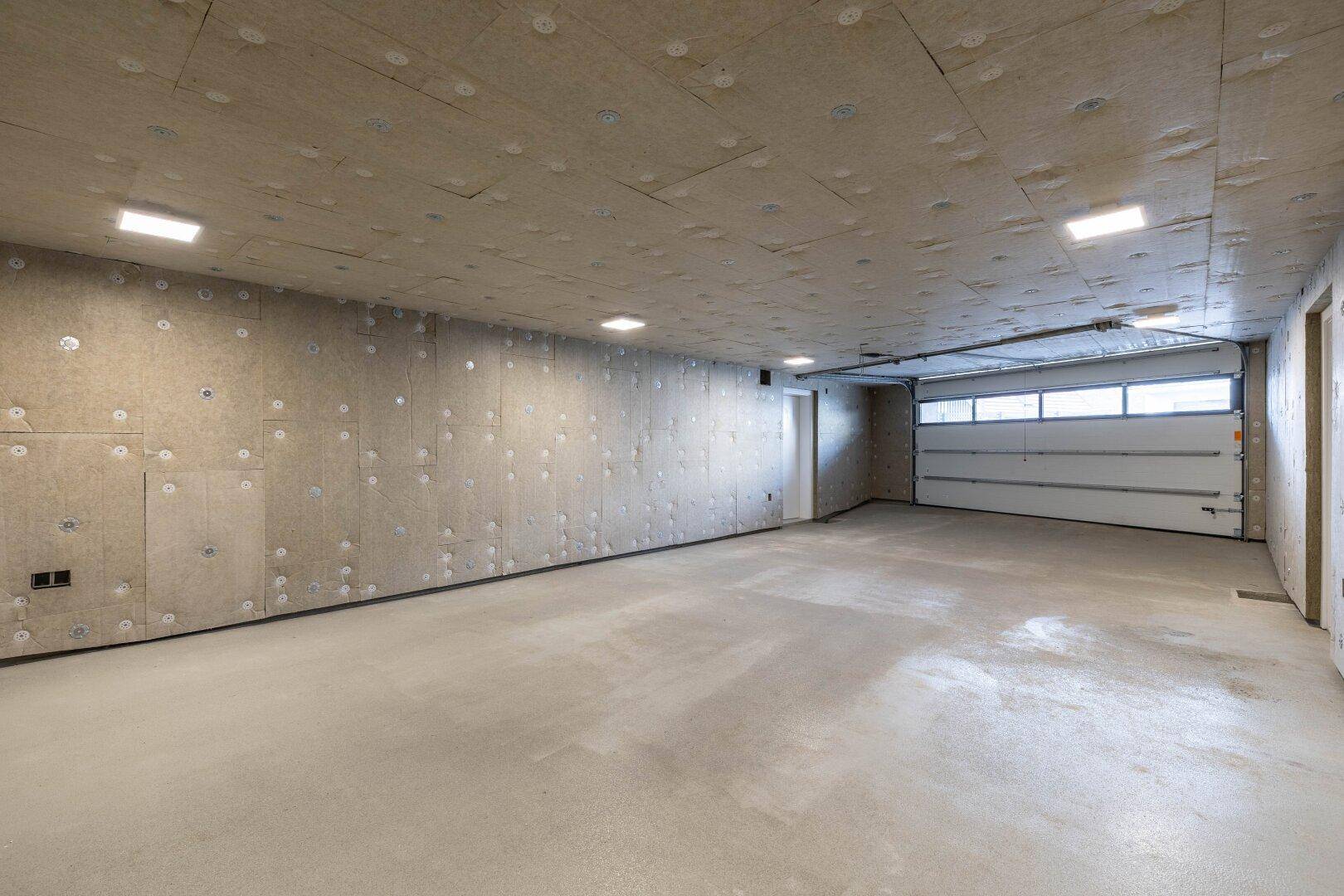 Geräumige Tiefgarage mit Betonboden und Rolltor, bereit für die Nutzung.