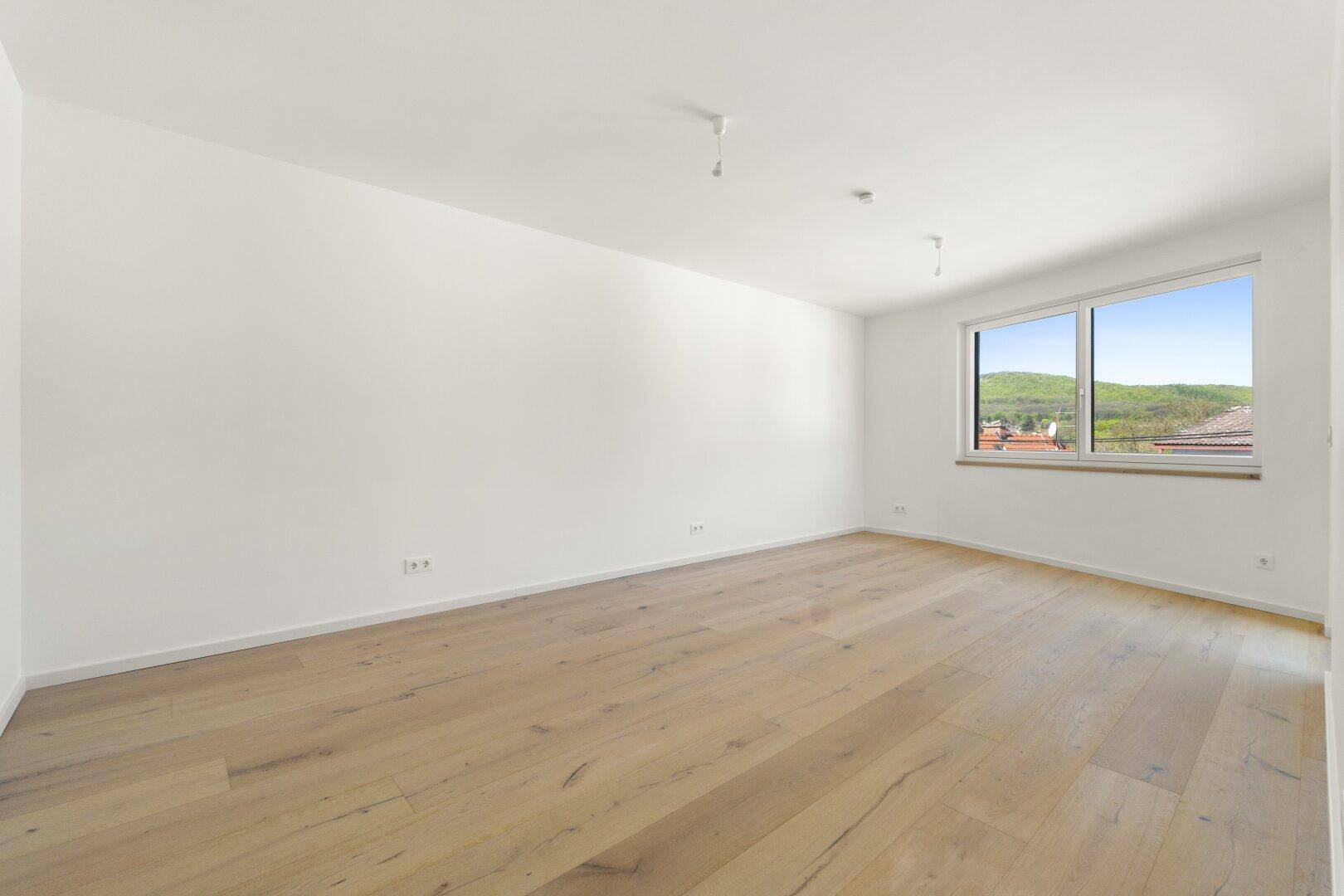 Geräumiger, heller Raum mit Holzboden und großen Fenstern, die einen weiten Blick bieten.