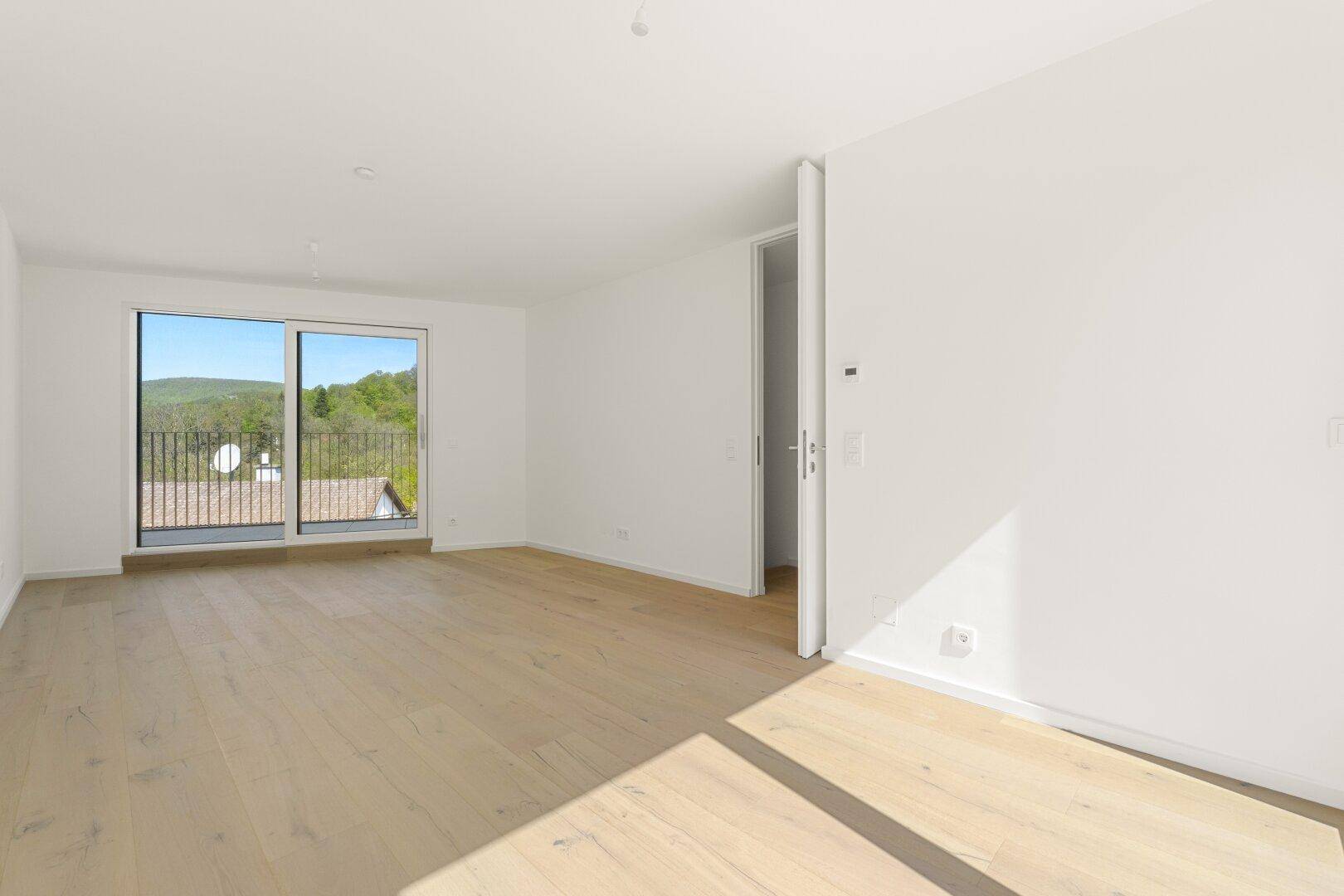 Geräumiges Schlafzimmer mit Holzboden und direktem Zugang zu einem sonnigen Balkon.