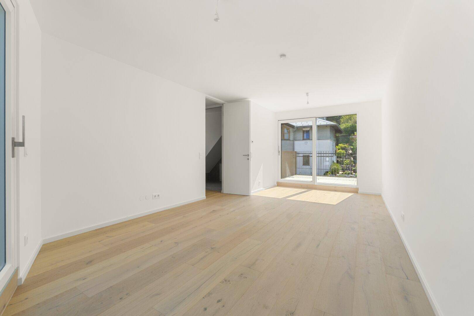 Heller Wohnraum mit Holzboden und zwei Zugängen zu Außenbereichen, ideal für natürliches Licht.