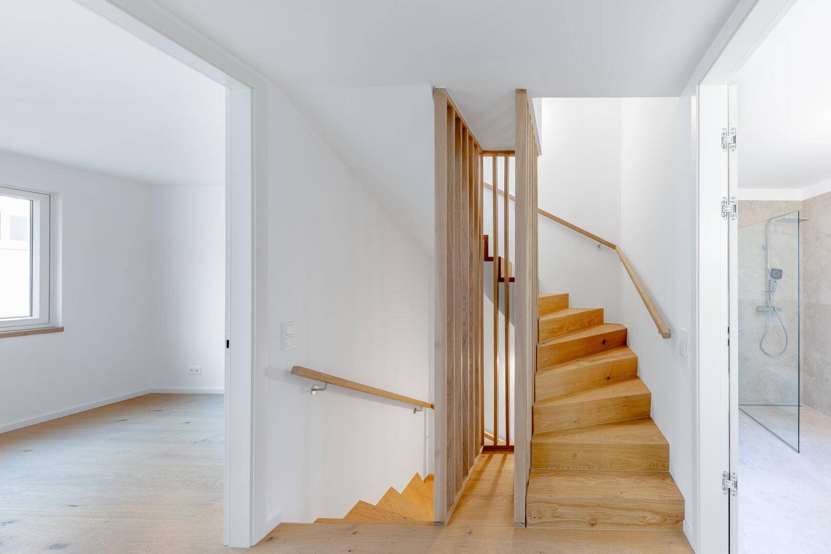Moderner Treppenaufgang aus Holz mit minimalistischem Geländer, der verschiedene Ebenen verbindet.