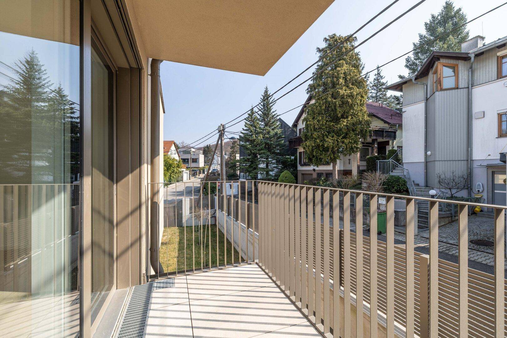 Geräumiger Balkon mit modernem Geländer und Blick auf die umliegende Wohngegend und Straße.