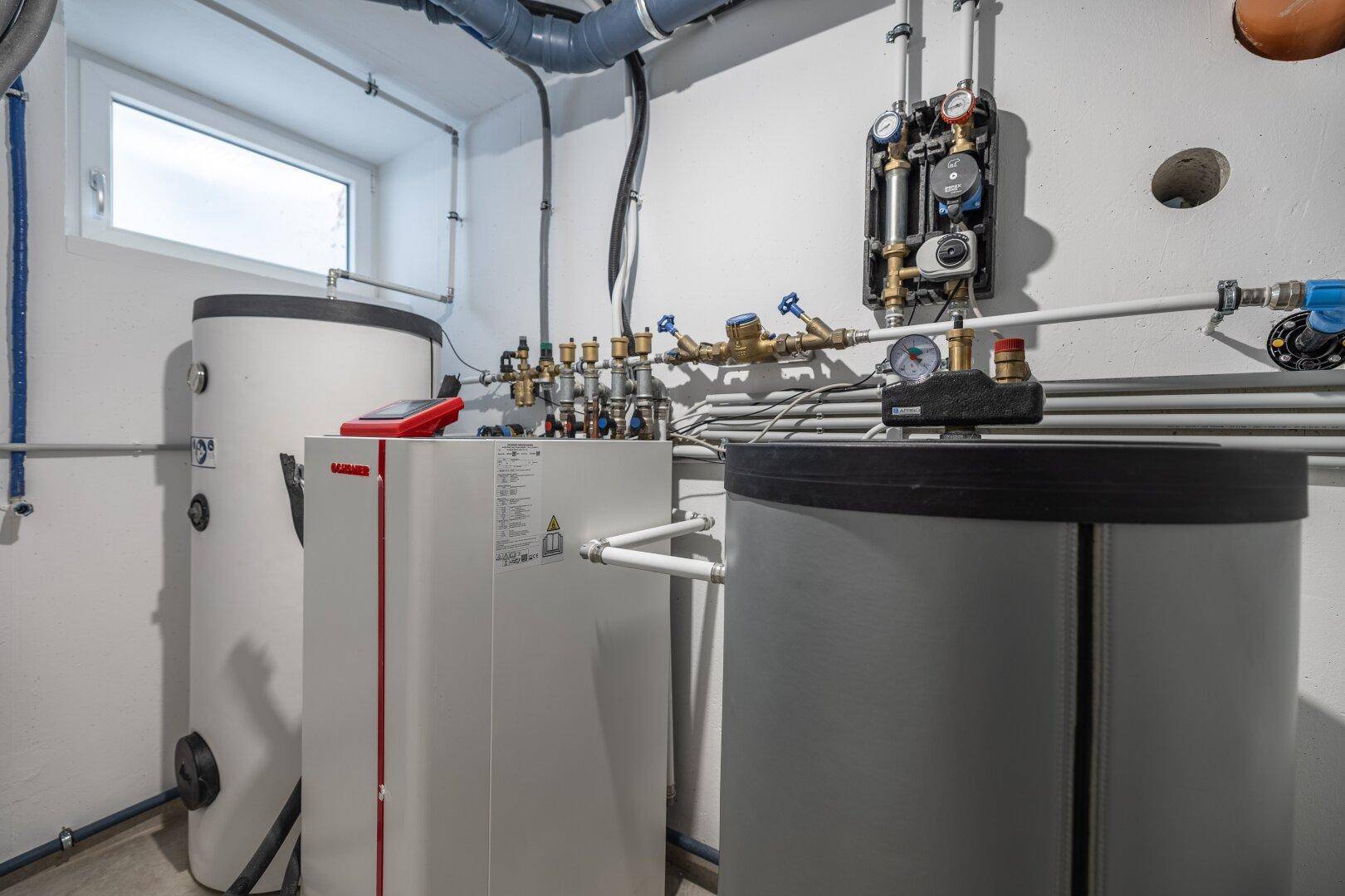 Technikraum mit Heizungsanlage, Warmwasserspeichern und Rohrleitungen, gut organisiert und funktional.