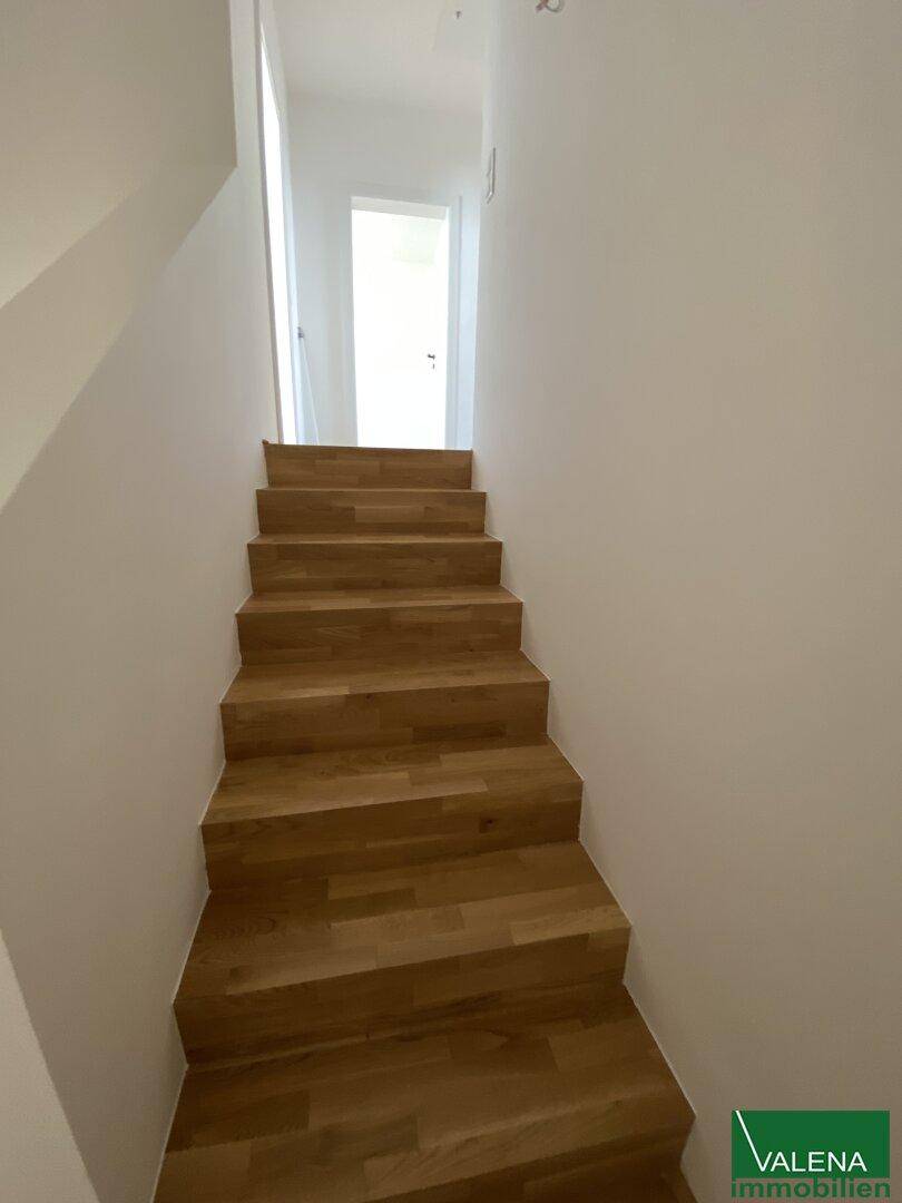Moderne Holztreppe verbindet die Etagen in einem hellen, neuwertigen Treppenhaus.