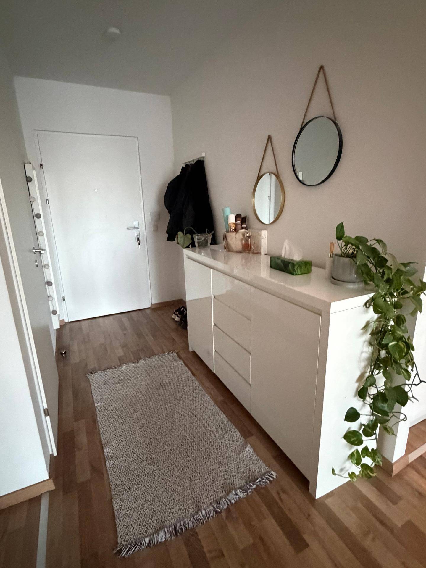 Eingangsbereich mit weißem Sideboard, runden Spiegeln und Garderobe.