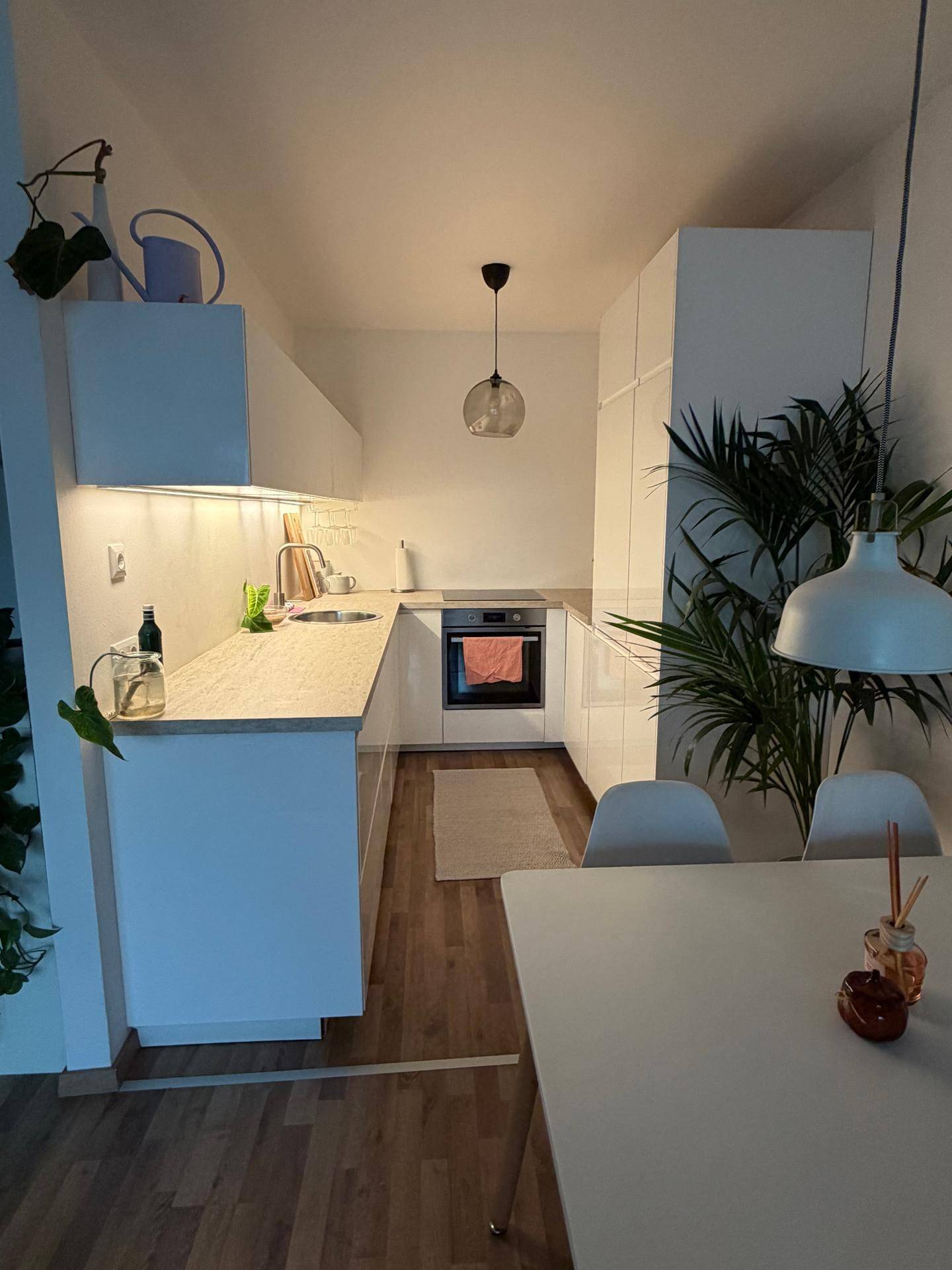 Moderne Einbauküche mit weißen Hochglanzfronten, Holzarbeitsplatte und integriertem Backofen.