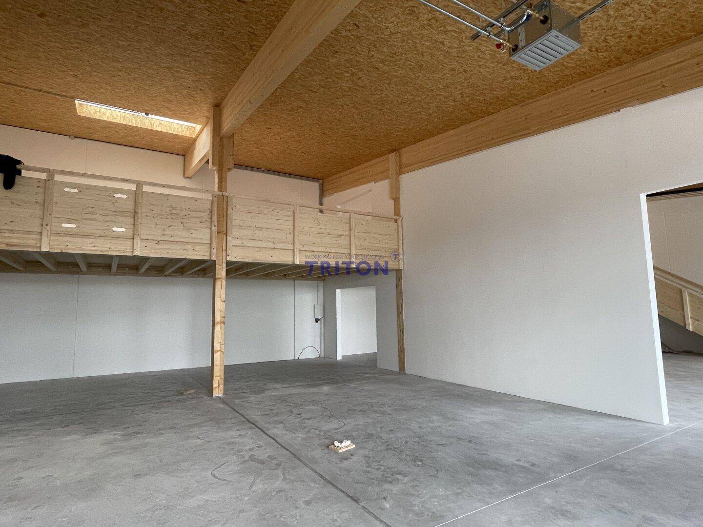 Geräumige Gewerbefläche mit Betonboden, Holzkonstruktion und einer Holzgalerie, hell und offen gestaltet.